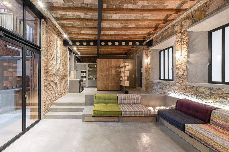 Discover how an old carpenter’s workshop in Barcelona was transformed into a dual residence that balances preserved stone walls with sleek concrete finishes.