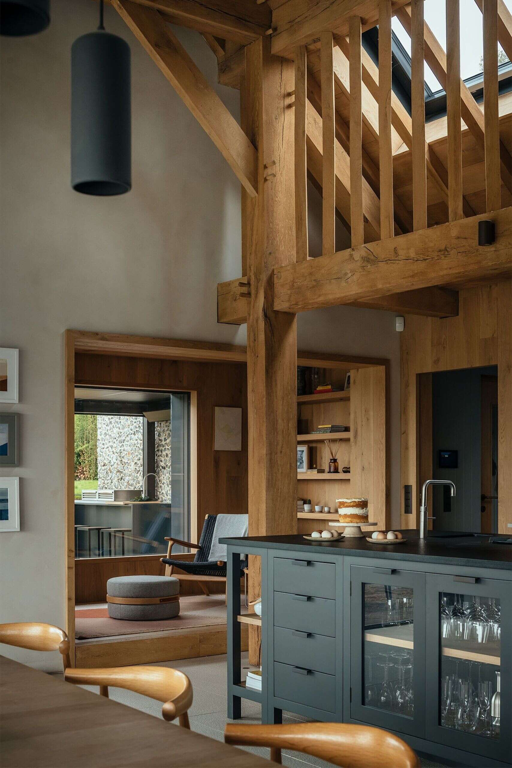 This barn-inspired design interior has a black kitchen and a fireplace separating the dining area from the living room.