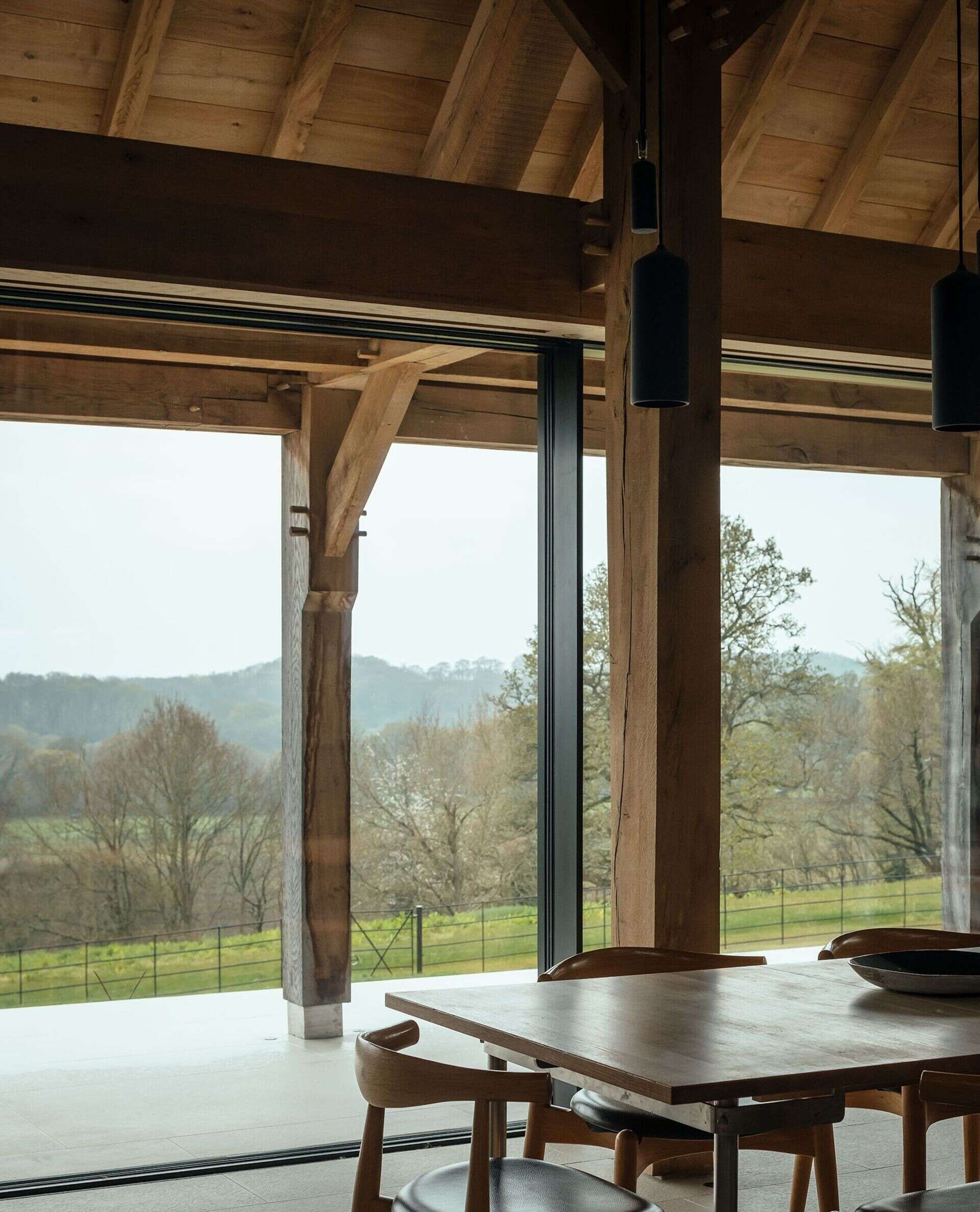 This barn-inspired design interior has a black kitchen and a fireplace separating the dining area from the living room.