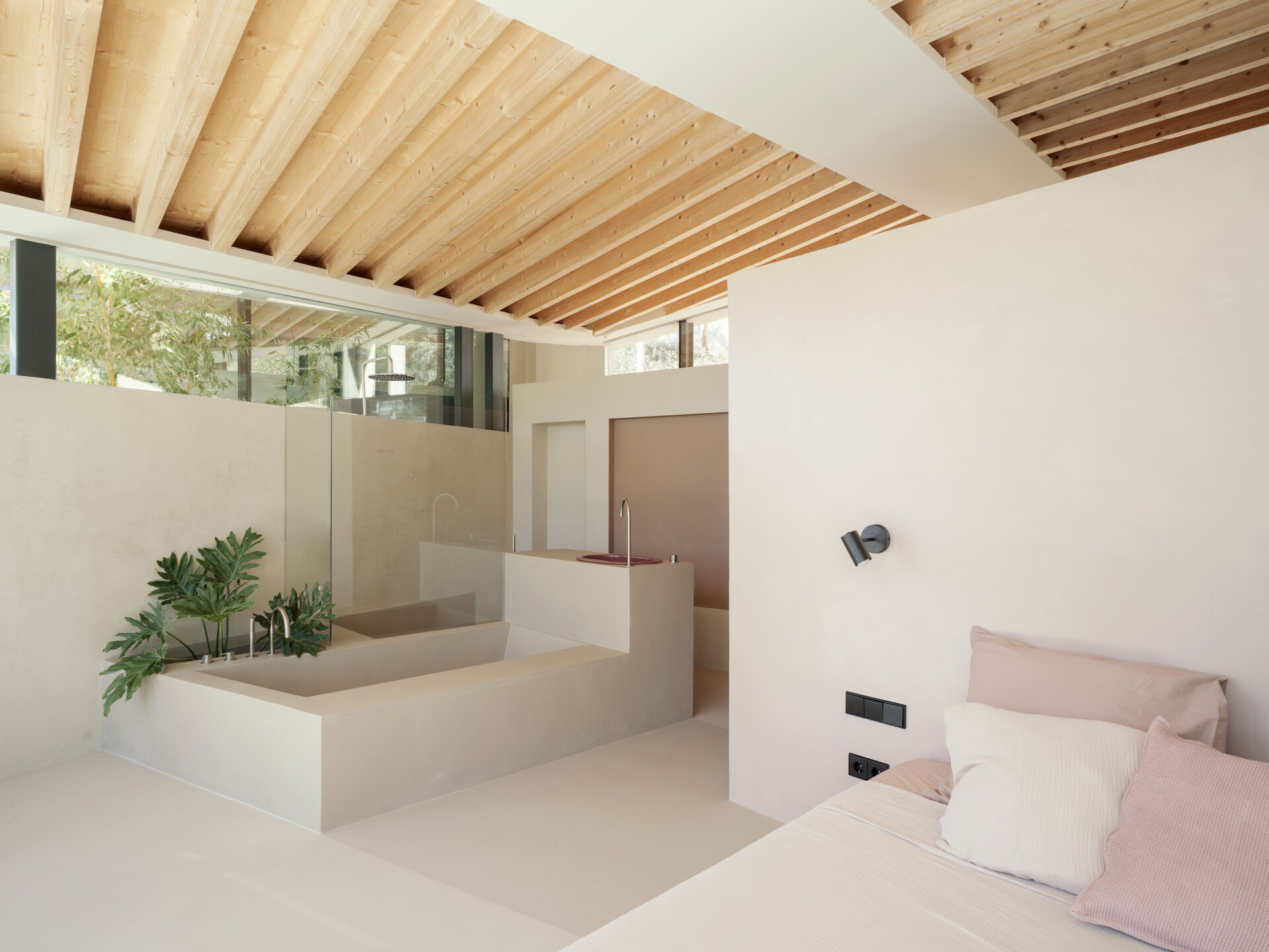 At Can Tudó, the bedrooms flow seamlessly into open bathrooms, with freestanding tubs, sinks, and wardrobes arranged as sculptural dividers. These floating elements define space without enclosing it, allowing every corner to capture uninterrupted views of the bay.