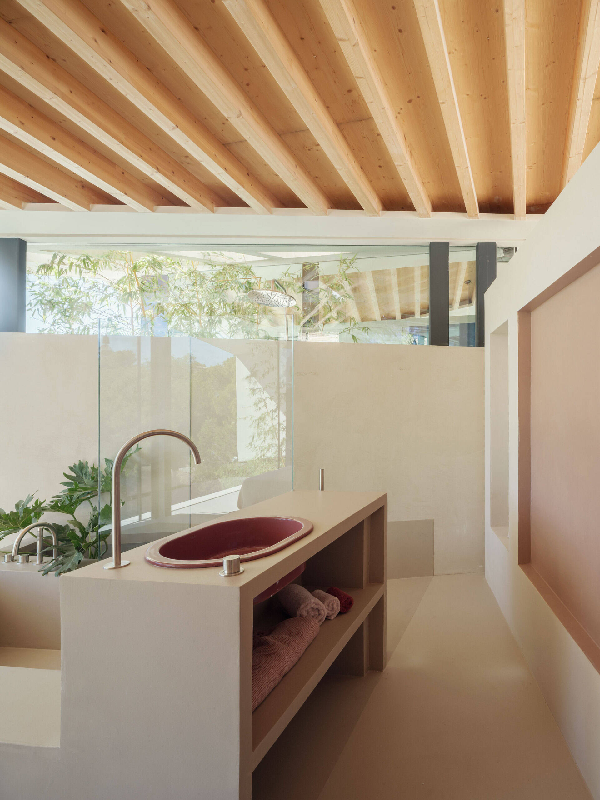 At Can Tudó, the bedrooms flow seamlessly into open bathrooms, with freestanding tubs, sinks, and wardrobes arranged as sculptural dividers. These floating elements define space without enclosing it, allowing every corner to capture uninterrupted views of the bay.