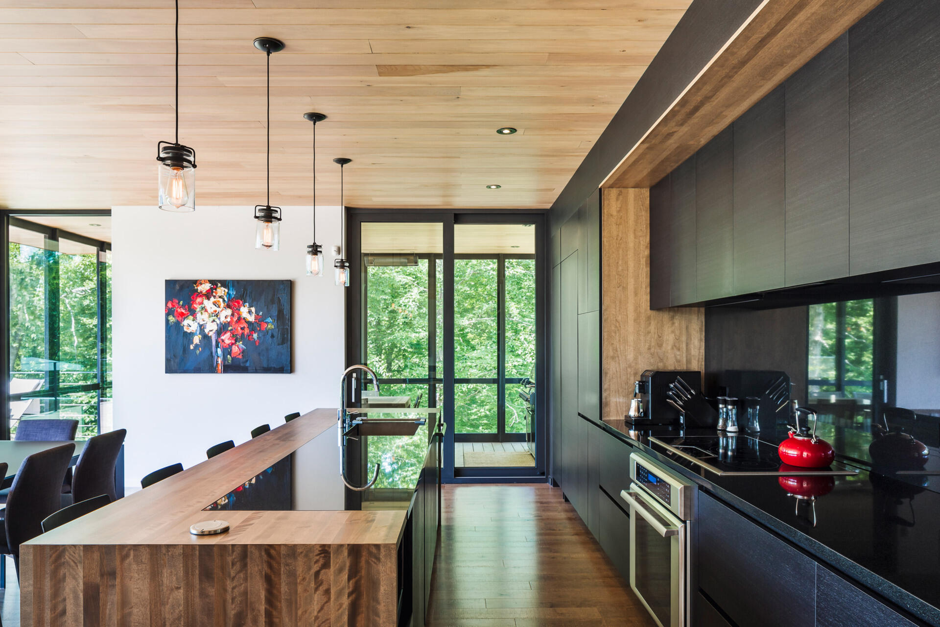 Black ash cabinetry meets warm wood accents in a streamlined kitchen that opens onto a lakeview deck.