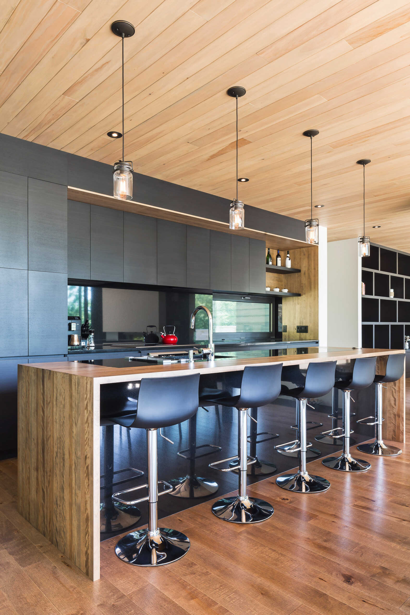 Black ash cabinetry meets warm wood accents in a streamlined kitchen that opens onto a lakeview deck.