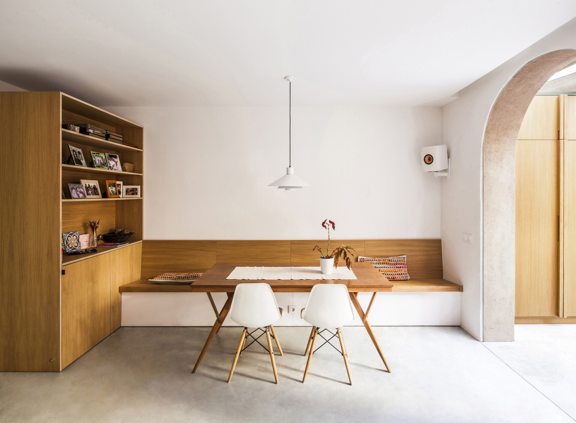 The reconfigured ground floor includes a dining area with a built-in banquette and cabinet with shelving. Its placement maximizes space while keeping the area in direct dialogue with the patio and the other social spaces.