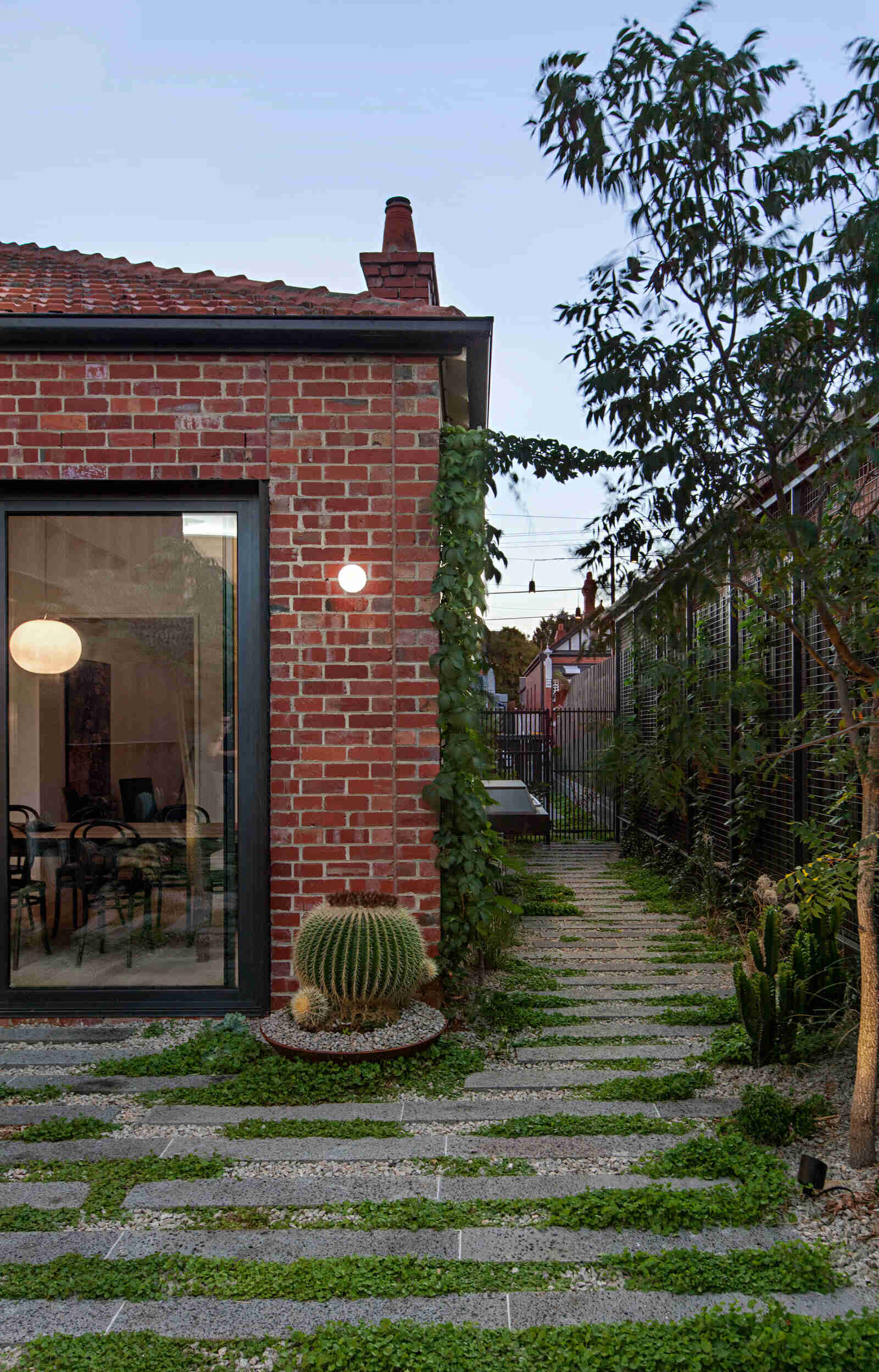 A serene garden path guides visitors down the side of the Edwardian cottage, leading to the backyard extension.