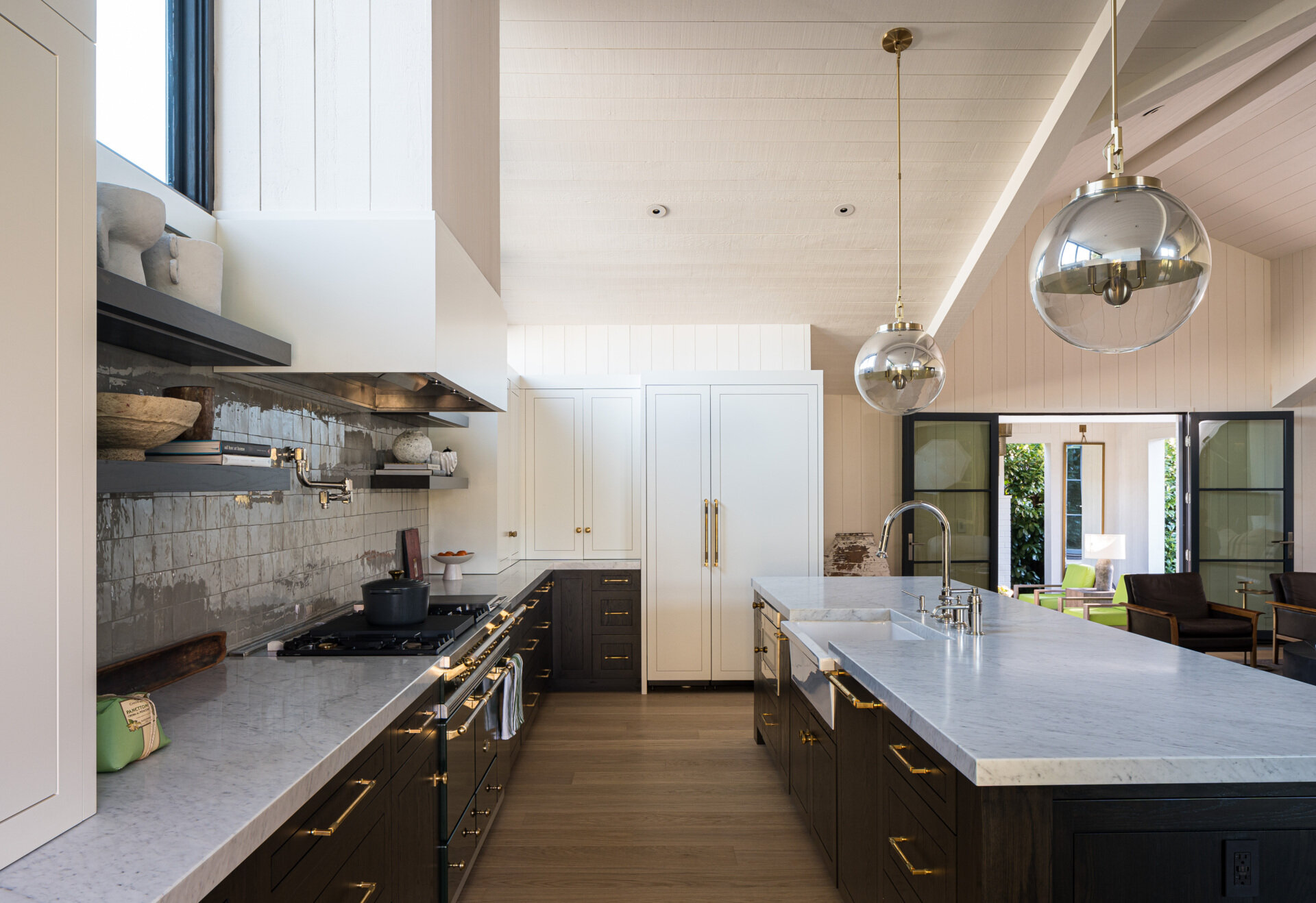 In this contemporary kitchen, triangular windows draw in both sunlight and landscape views, creating a distinctive connection between daily routines and the beauty outside. Together, the kitchen and dining spaces embody the remodel’s central vision: openness, light, and a harmonious relationship with the outdoors.