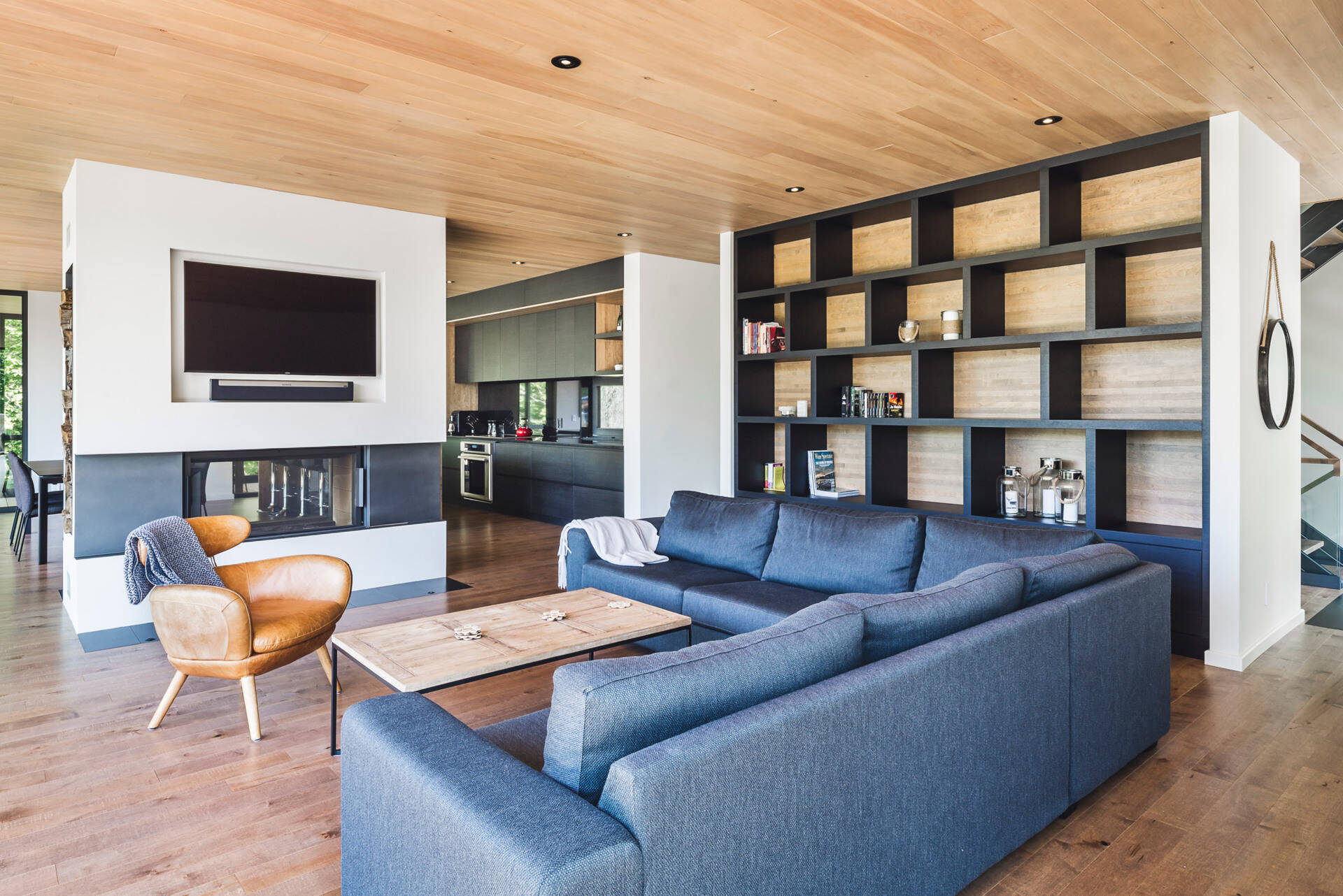 A double-sided fireplace, custom TV cut-out, and floor-to-ceiling bookshelf make this living room both sleek and cozy.