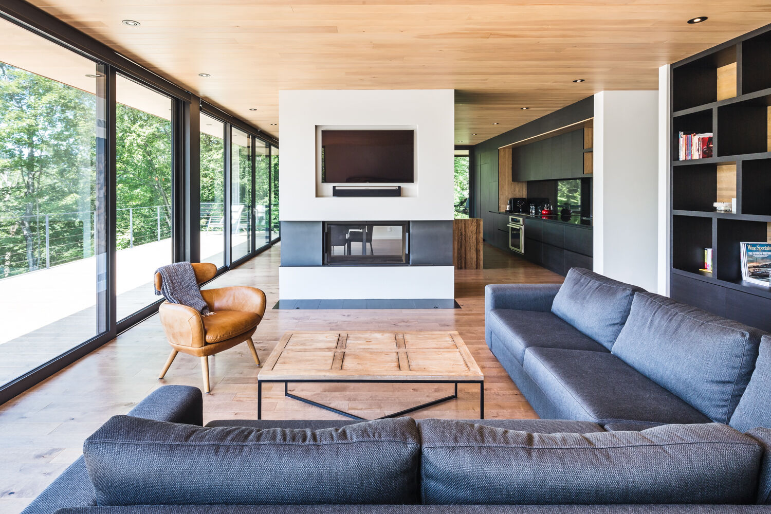 A double-sided fireplace, custom TV cut-out, and floor-to-ceiling bookshelf make this living room both sleek and cozy.