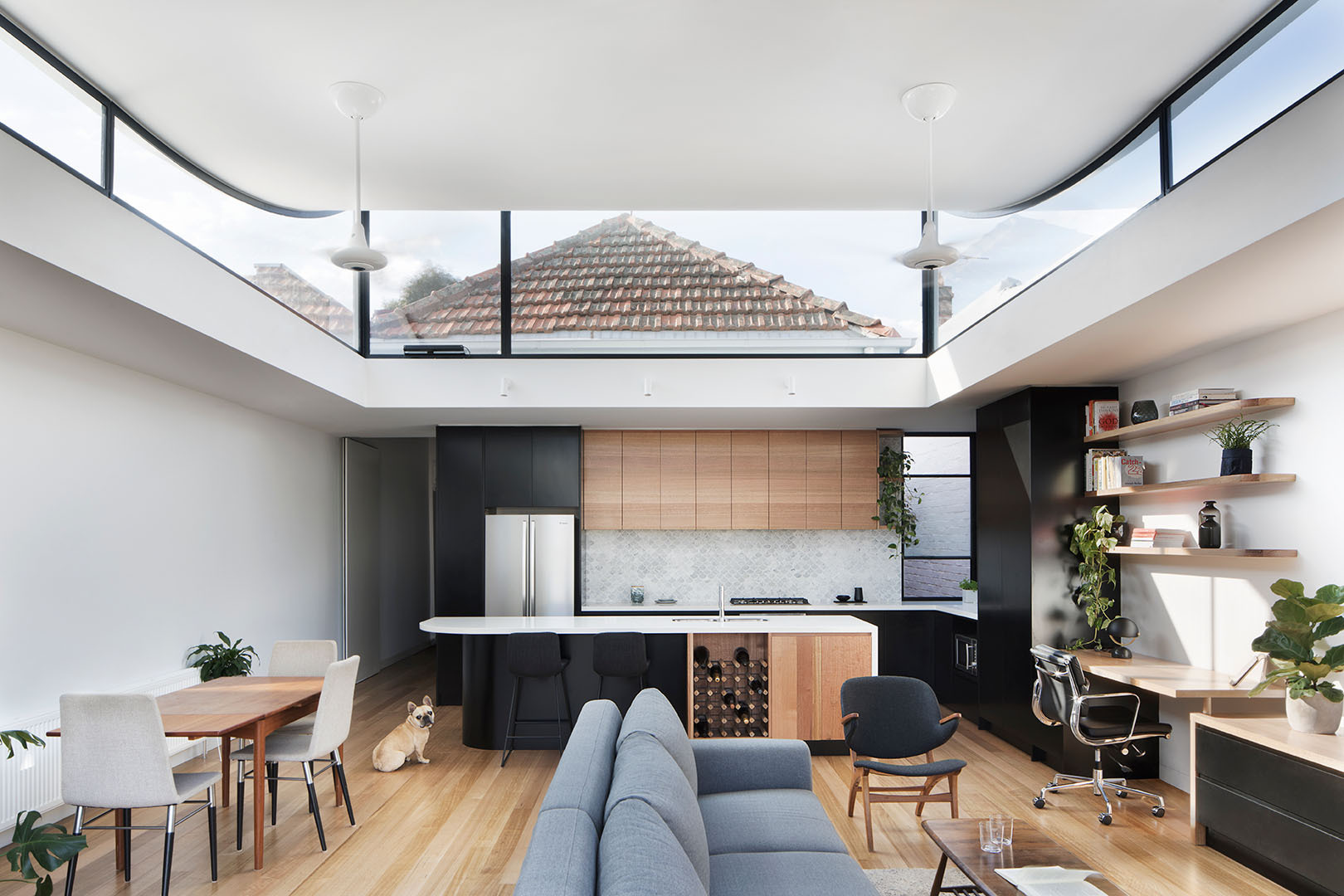 A curved roofline with clerestory windows fills the open plan living, dining and kitchen with sunlight, making the compact terrace feel expansive.