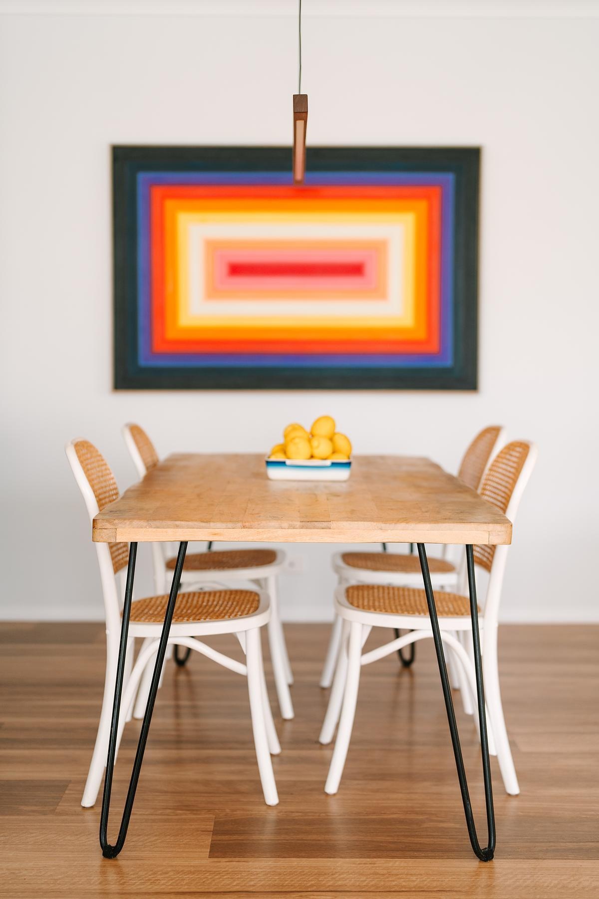 Flowing from the kitchen, the dining area naturally draws family and friends together. Vibrant, colorful commissioned artwork by Mat Vaughan adds energy and personality, making the space feel lively and unique.