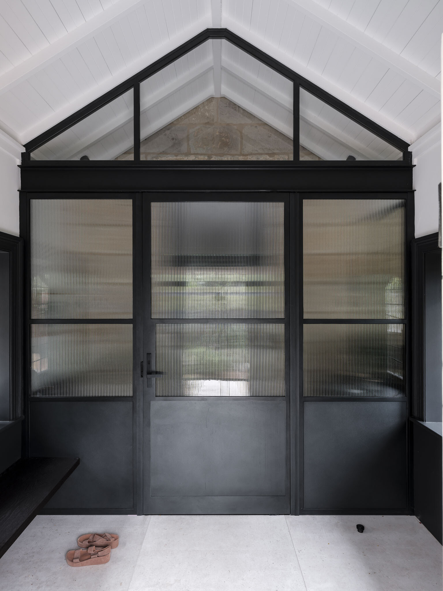 The vestibule acts as a threshold between eras. Here, the design does not attempt to erase history but instead highlights the transition, allowing heritage masonry to stand beside refined steel framing and new openings. This sense of passage sets the tone for the house as a whole.