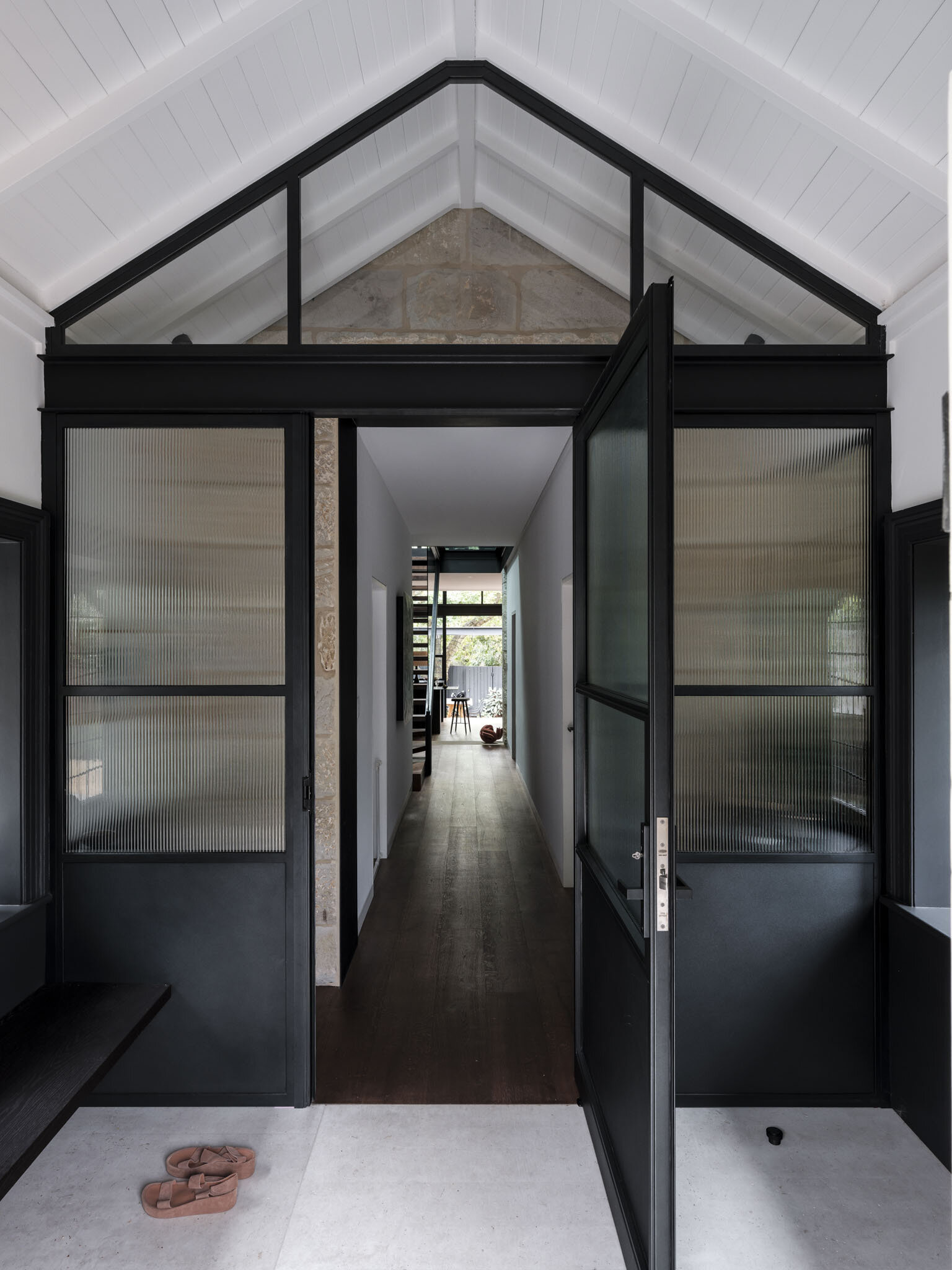 The vestibule acts as a threshold between eras. Here, the design does not attempt to erase history but instead highlights the transition, allowing heritage masonry to stand beside refined steel framing and new openings. This sense of passage sets the tone for the house as a whole.