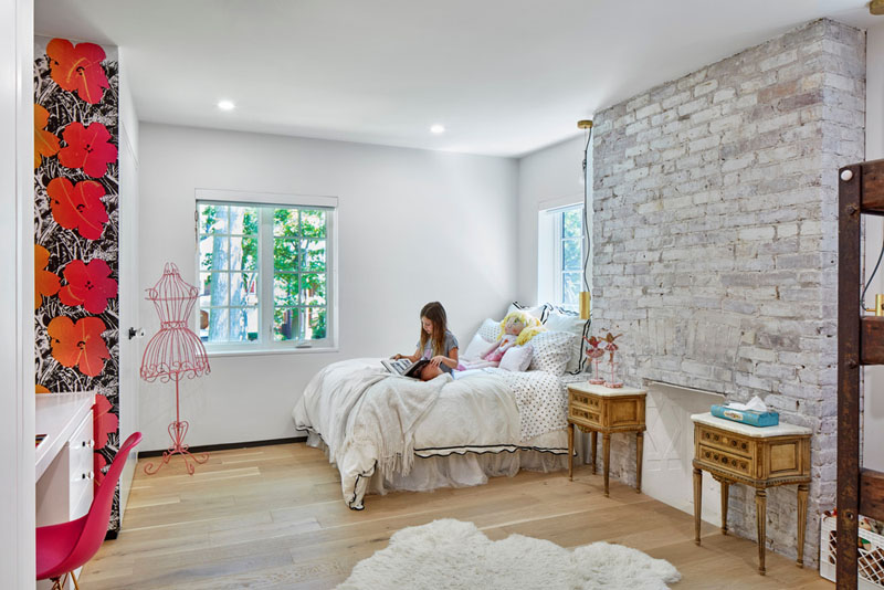 A girl's bedroom in a renovated heritage home includes the original fireplace.