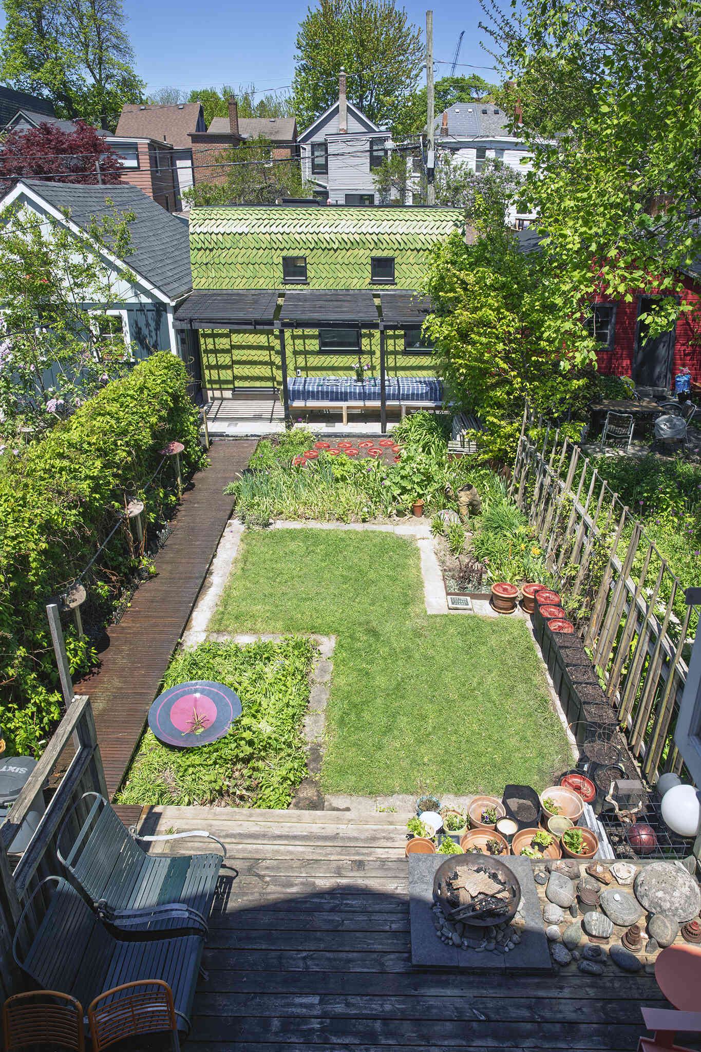 A Toronto laneway garage transformed into The Dragon, bold, playful, and full of architectural charm. It has a pergola and is covered in cedar shingles with a green pine tar finish.
