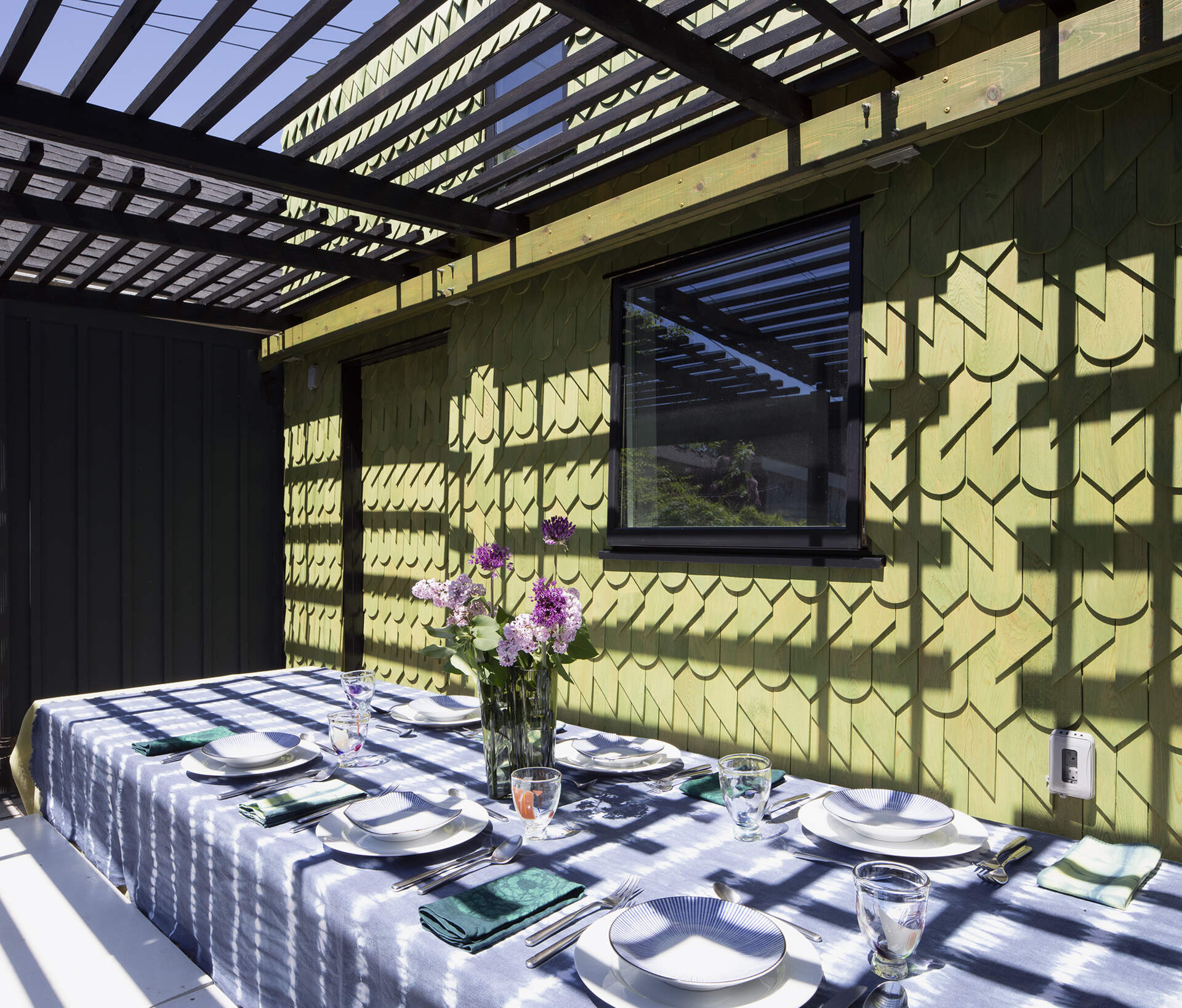 A Toronto laneway garage transformed into The Dragon, bold, playful, and full of architectural charm. It has a pergola and is covered in cedar shingles with a green pine tar finish.