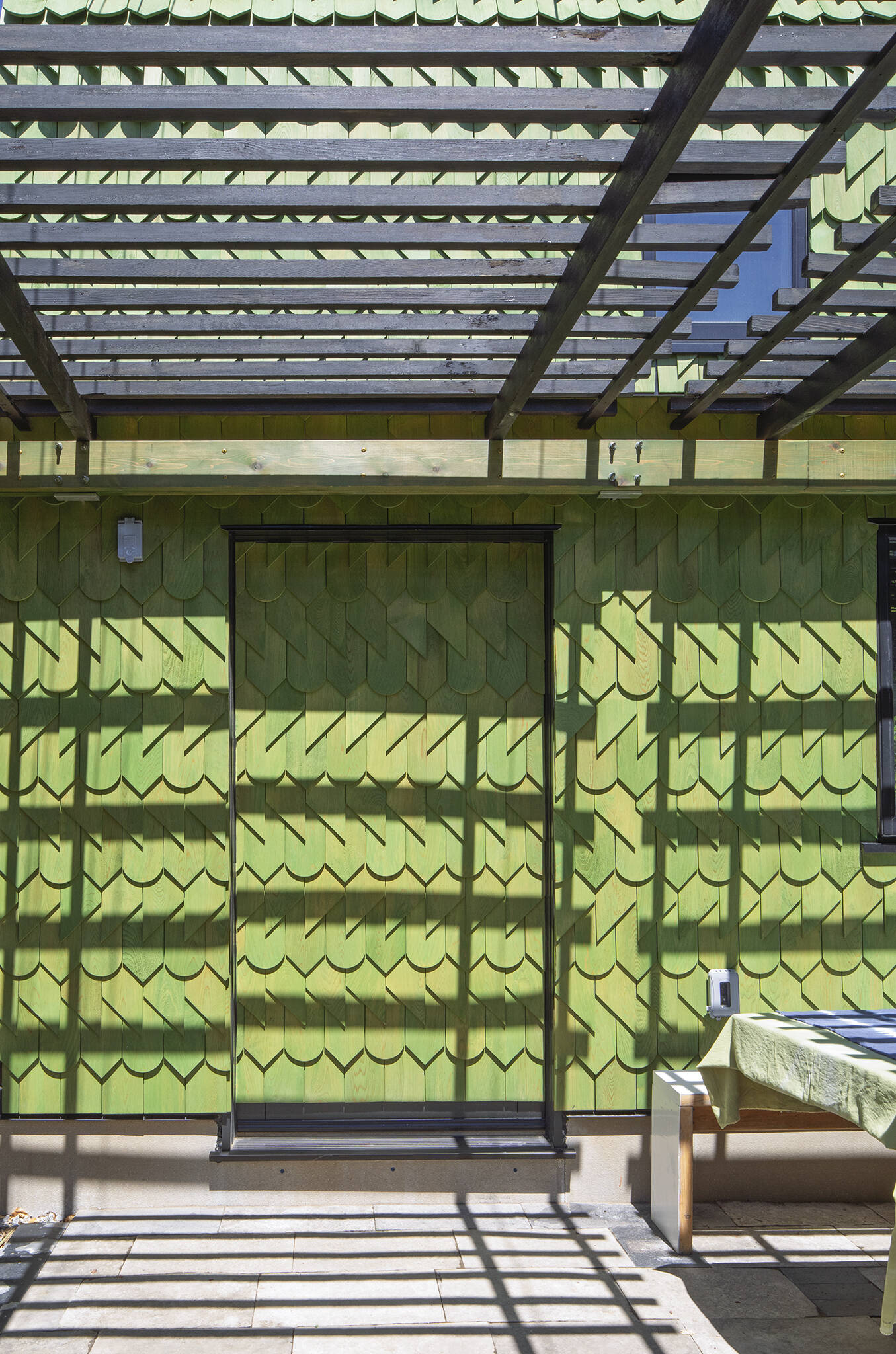 A Toronto laneway garage transformed into The Dragon, bold, playful, and full of architectural charm. It has a pergola and is covered in cedar shingles with a green pine tar finish.