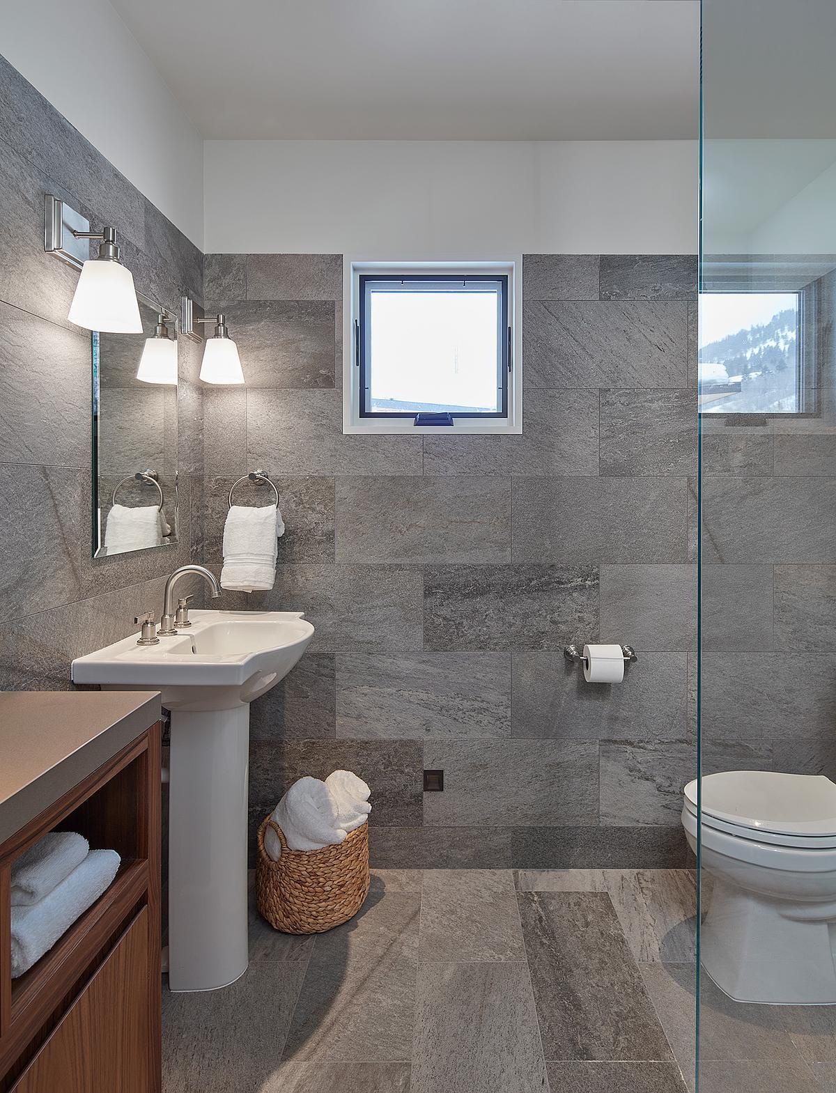 A modern bathroom with grey tiles in a guest house.