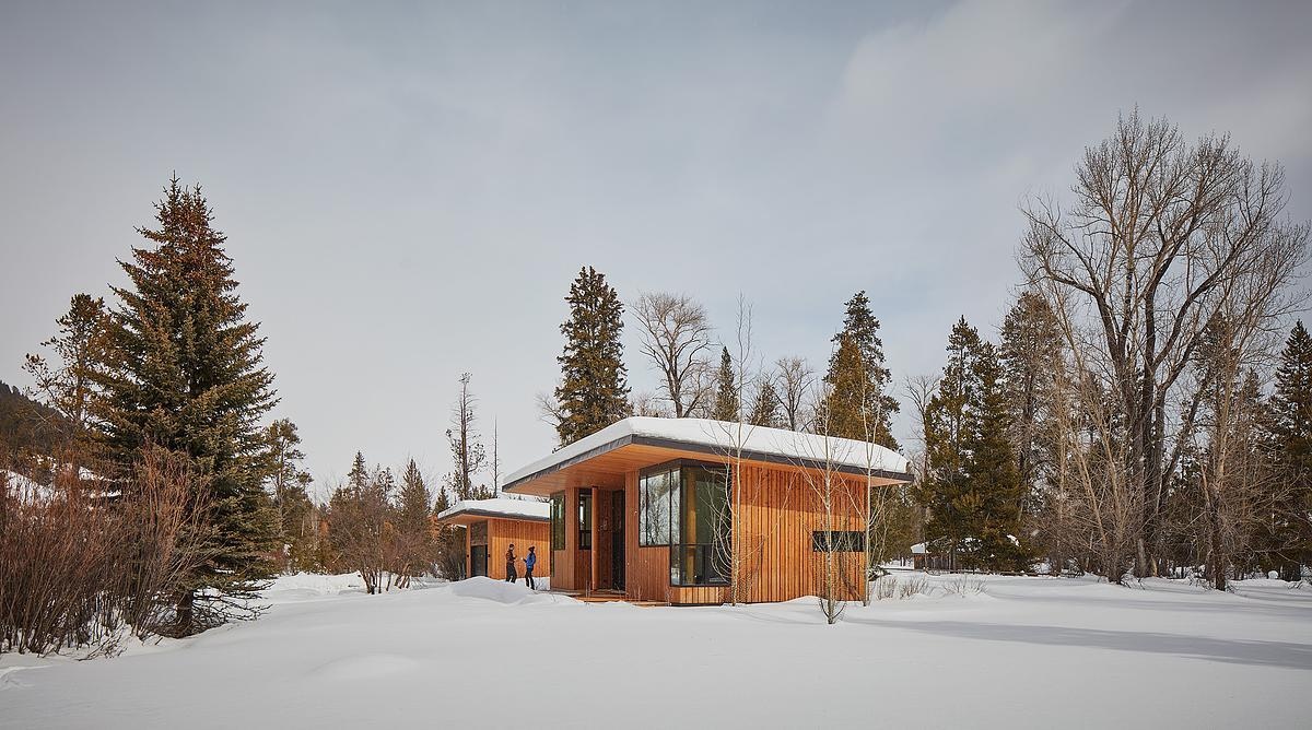A modern guest house and garage added to a log cabin.