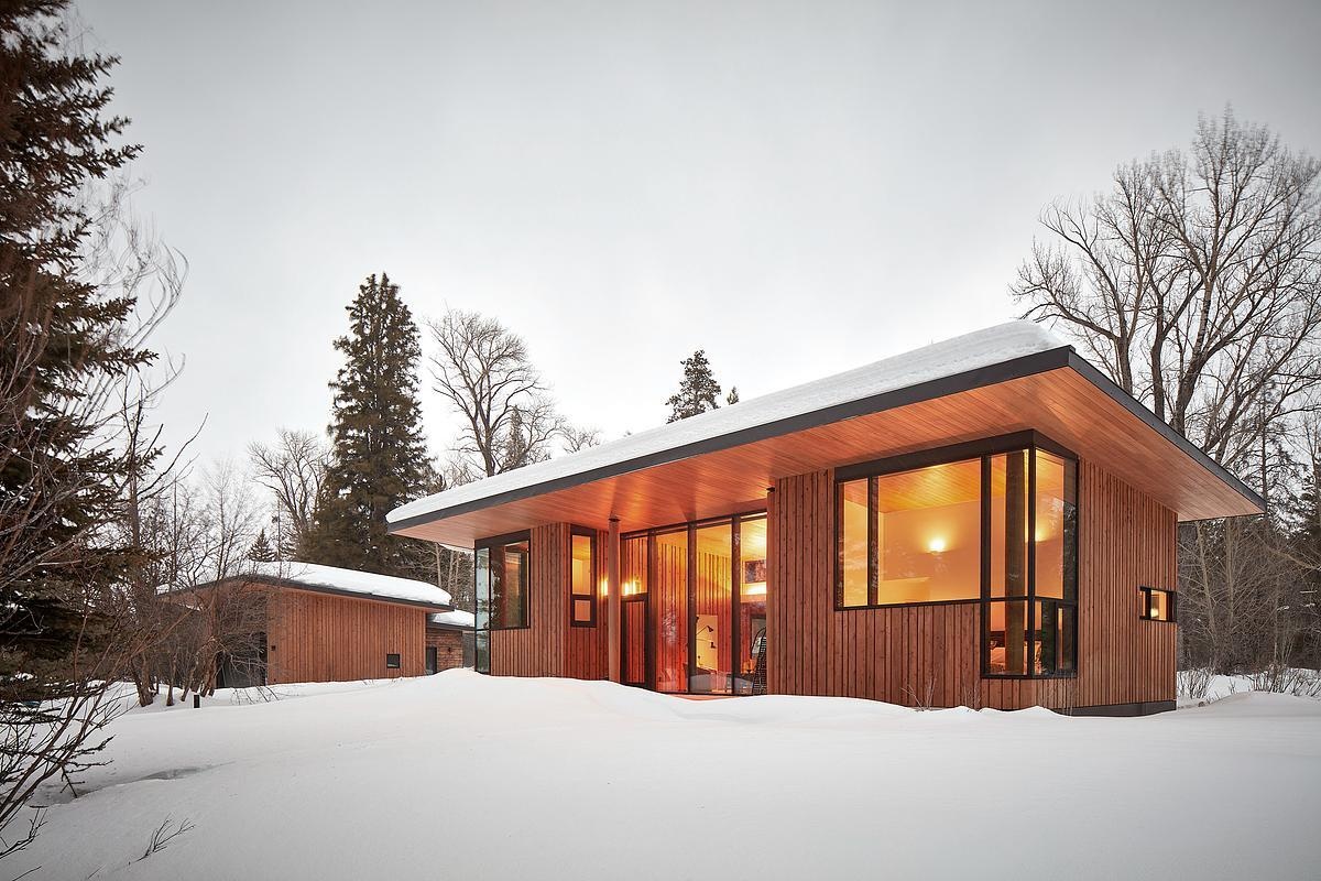 A modern guest house and garage added to a log cabin.