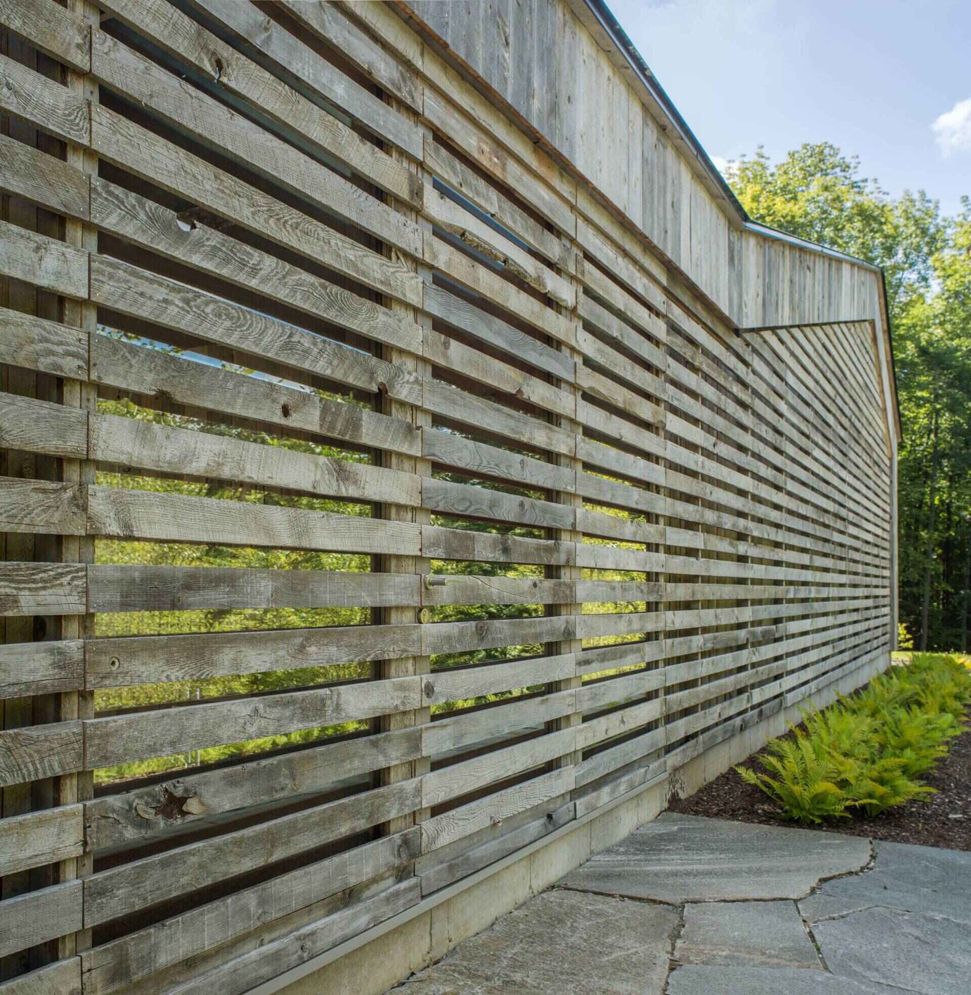 A Vermont guest house takes its shape from the classic woodshed, with gabled roofs that reimagine a familiar rural form. The house is clad in reclaimed snow fencing, weathered boards that give the structure instant character and texture.