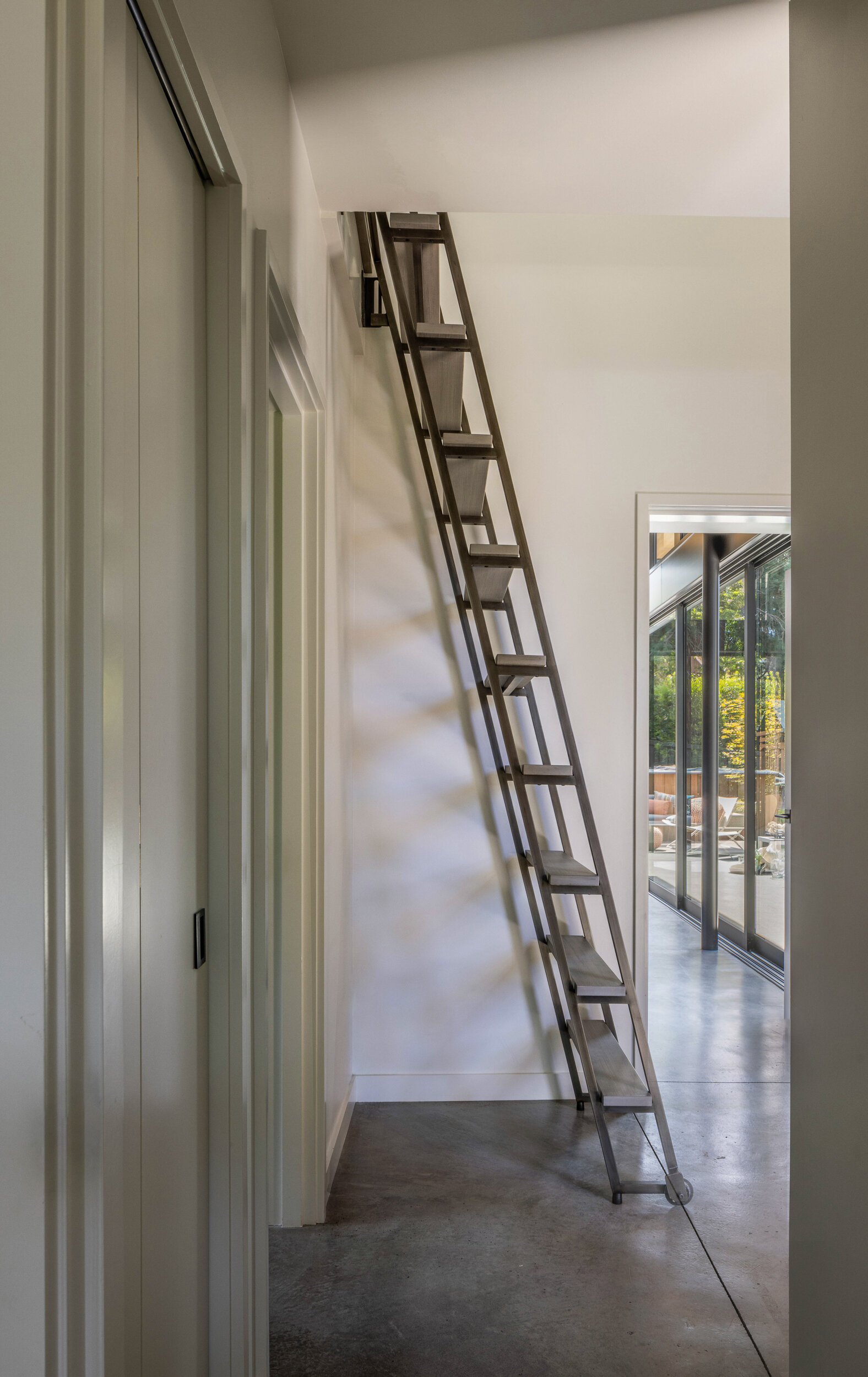 Custom steel ladder leading to a loft that doubles as office and extra sleeping space, adding flexibility for family gatherings and entertaining.