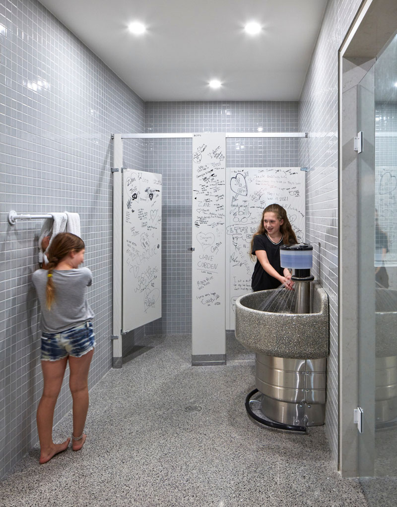 This renovated home has bathroom stall design and a communal sink with a foot-pedal faucet, adding a nostalgic, quirky twist to the lower level.