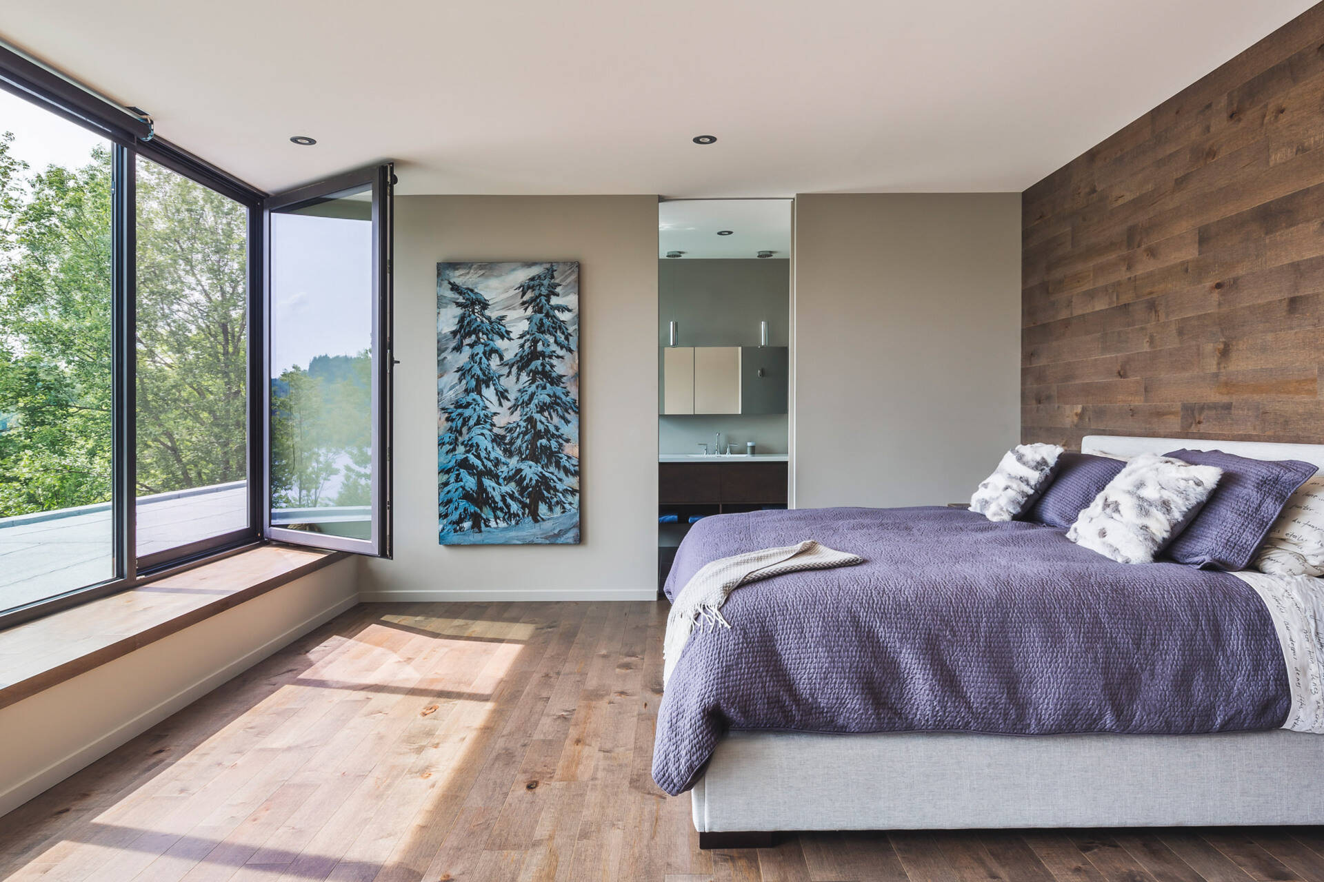 Wood accents, a window seat, and treetop views create a bedroom that feels both modern and serene.