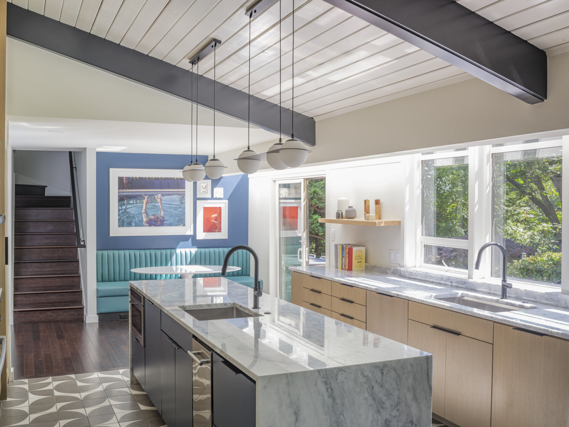 What was once walled-off is now the heart of the house. The new kitchen opens fully to the lounge and living room with a generous island at its center. Oak veneer cabinetry, stone counters, and Cle tile floors strike a balance between mid-century simplicity and modern function. 
