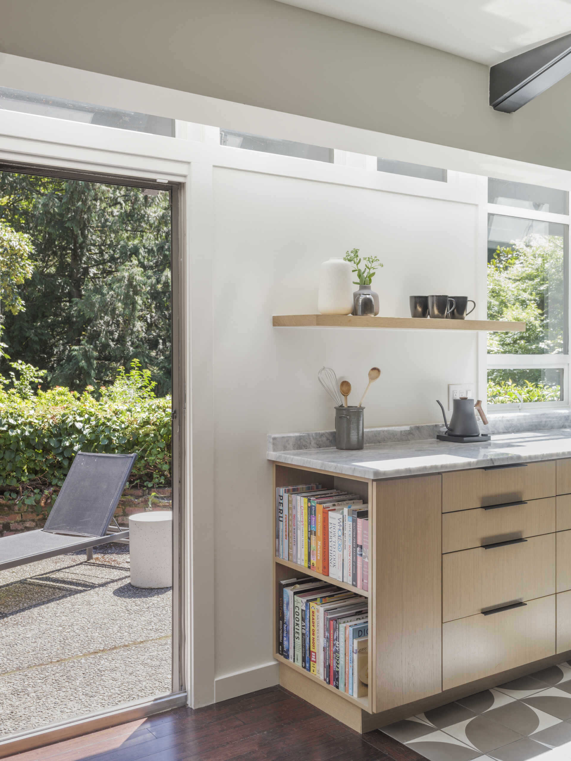 What was once walled-off is now the heart of the house. The new kitchen opens fully to the lounge and living room with a generous island at its center. Oak veneer cabinetry, stone counters, and Cle tile floors strike a balance between mid-century simplicity and modern function. 