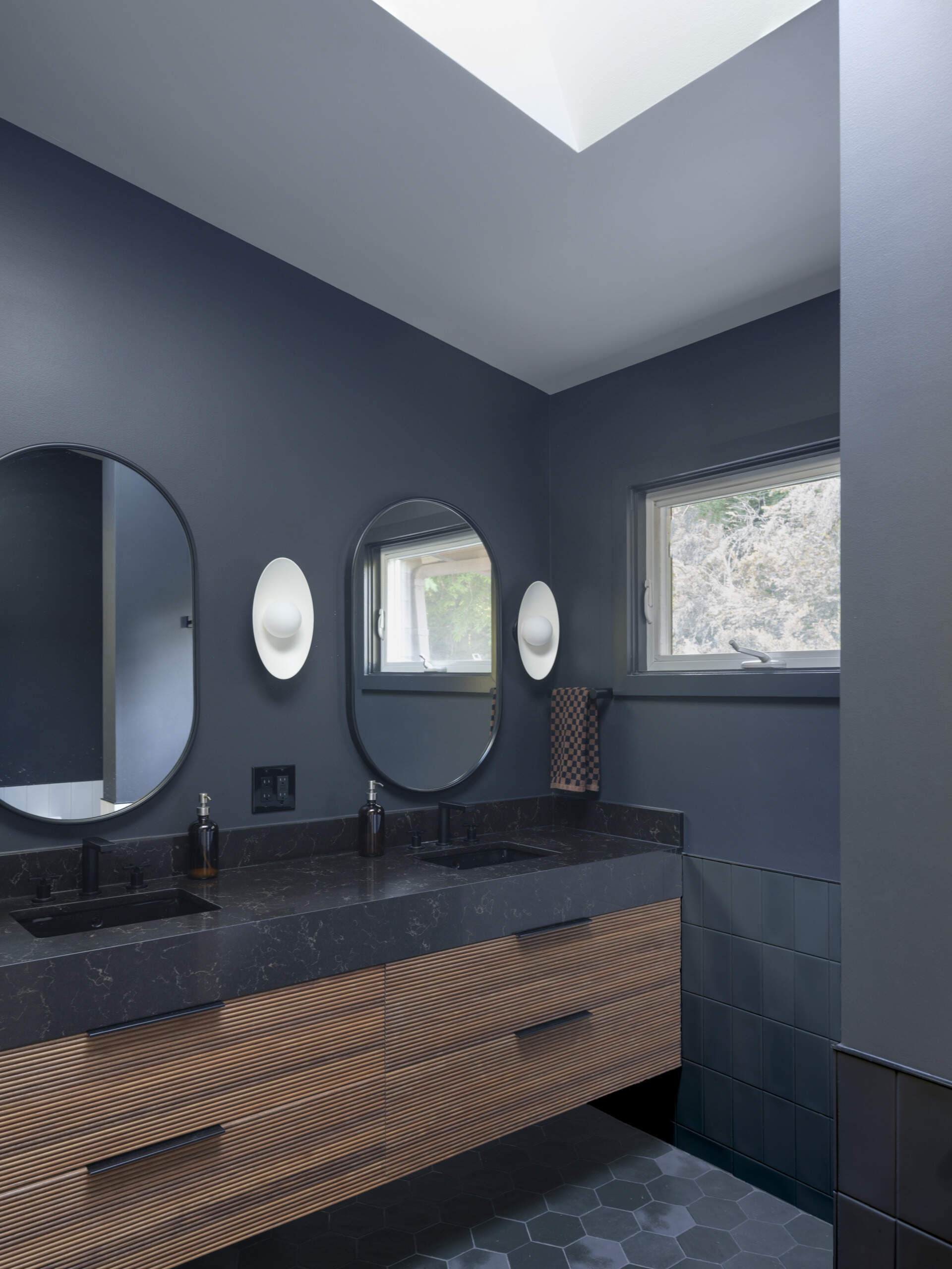 A modern grey bathroom with wood accents and hexagonal tile flooring.