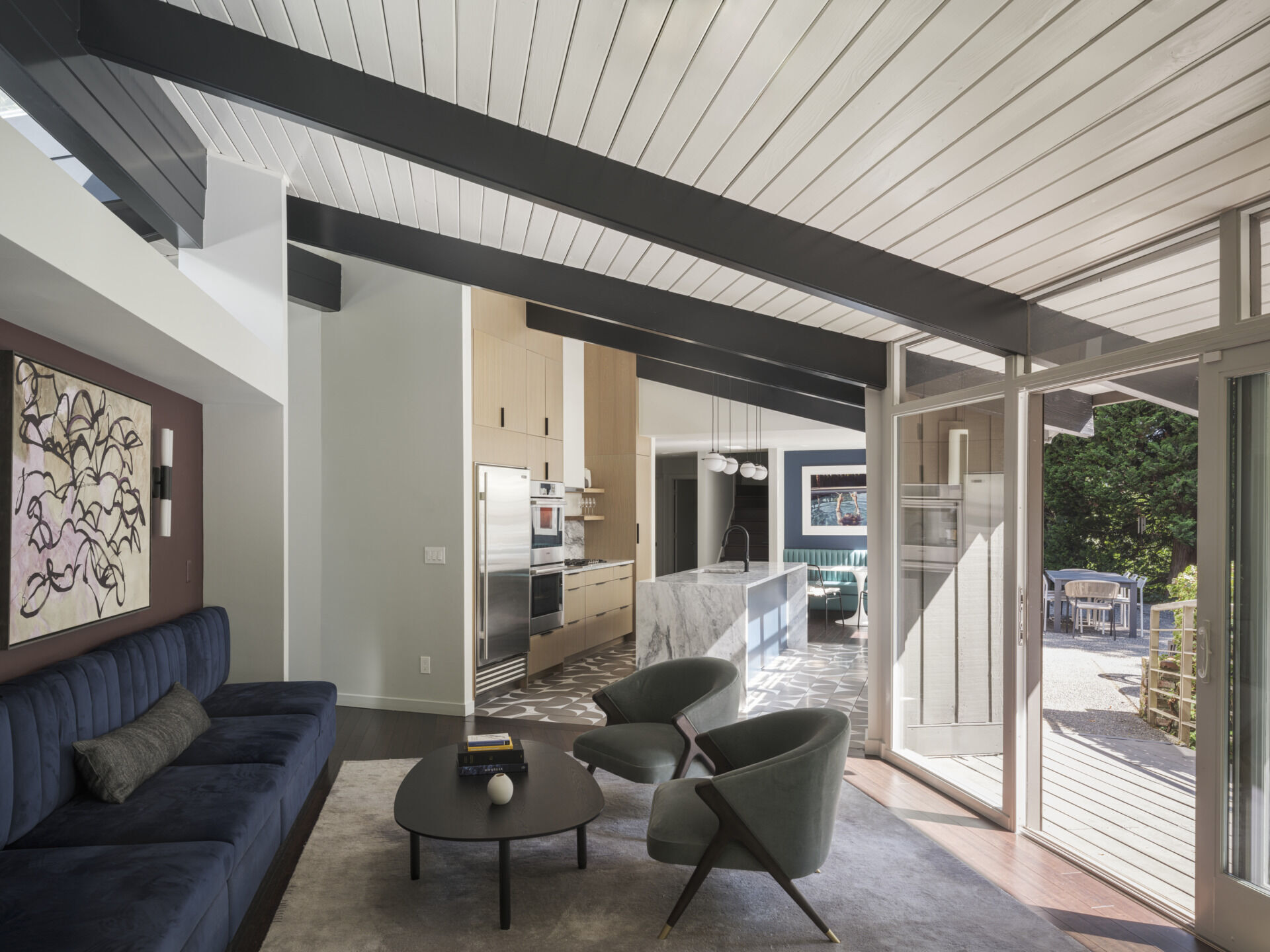 What was once walled-off is now the heart of the house. The new kitchen opens fully to the lounge and living room with a generous island at its center. Oak veneer cabinetry, stone counters, and Cle tile floors strike a balance between mid-century simplicity and modern function. 