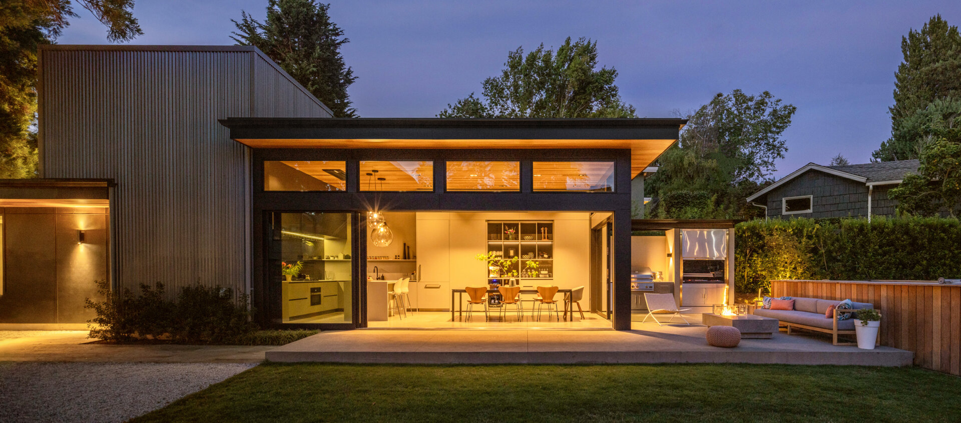 Seamless indoor-outdoor living with sliding glass doors, lawn, fire table, and swim spa, perfect for family gatherings and entertaining.