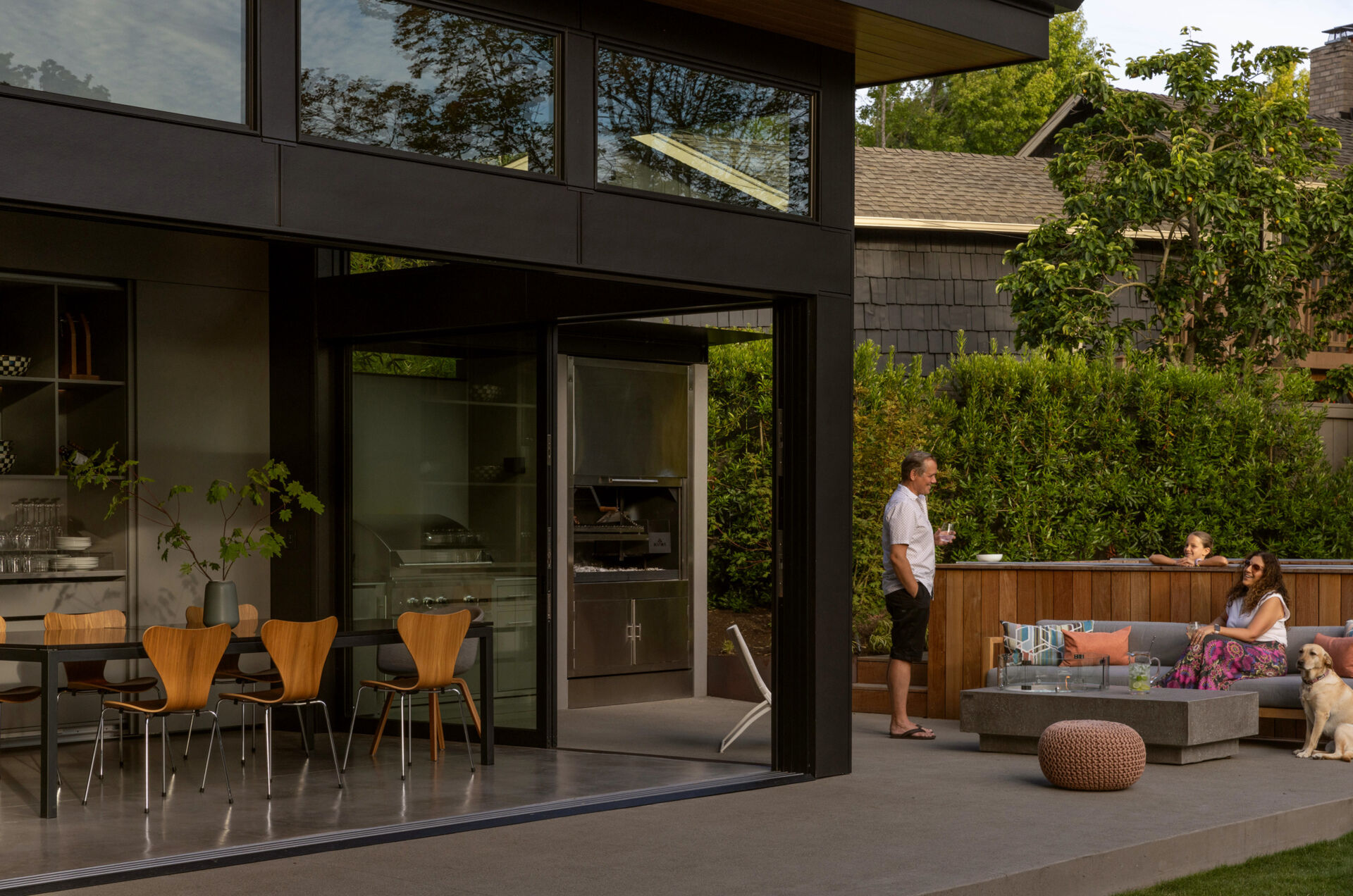 Seamless indoor-outdoor living with sliding glass doors, lawn, fire table, and swim spa, perfect for family gatherings and entertaining.
