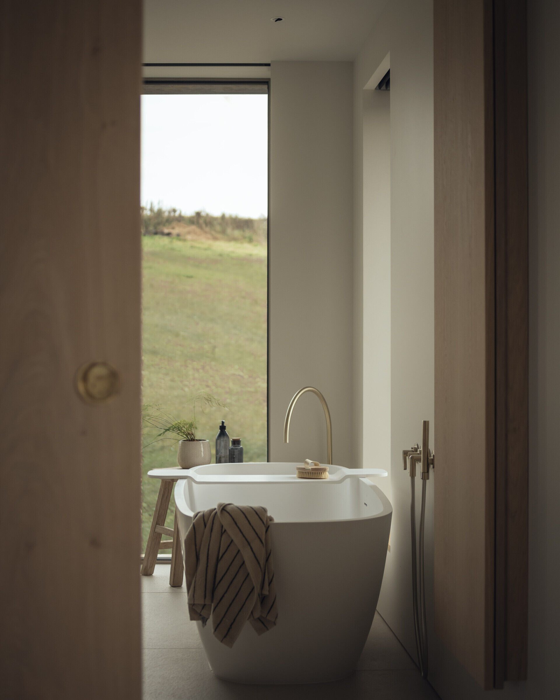A modern bathroom with a freestanding bathtub, a large window and a double vanity.