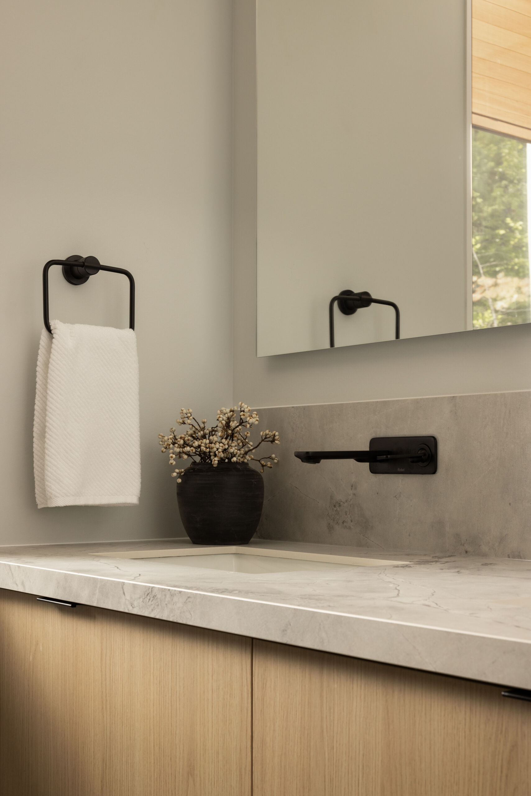 In this modern bathroom, a palette of white tiles and light wood brightens the space, underscoring the interior’s balance of contrast. The finish creates a clean, light-filled atmosphere, in dialogue with the natural light that filters through.
