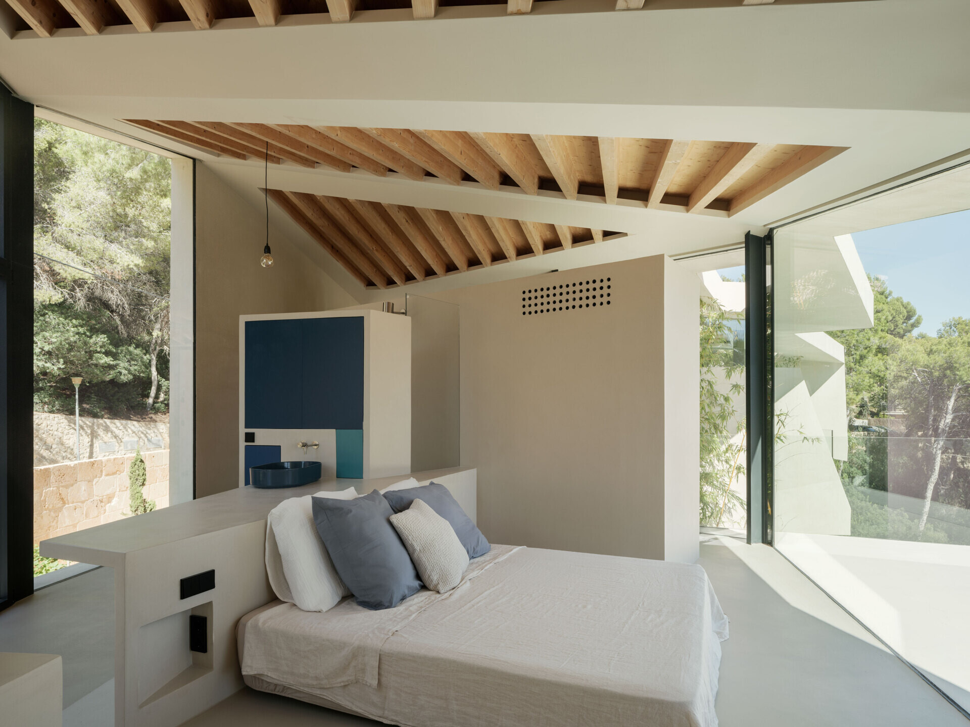 At Can Tudó, the bedrooms flow seamlessly into open bathrooms, with freestanding tubs, sinks, and wardrobes arranged as sculptural dividers. These floating elements define space without enclosing it, allowing every corner to capture uninterrupted views of the bay.