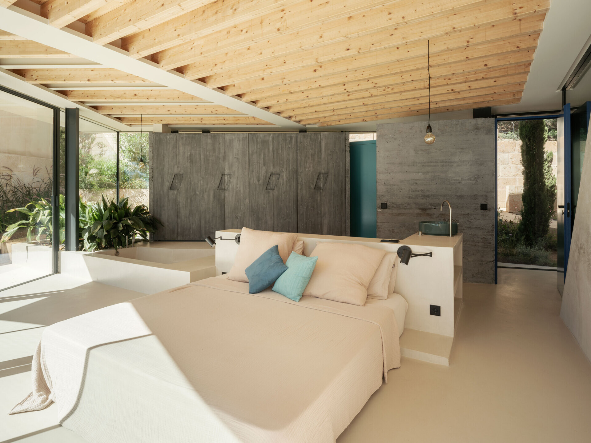 At Can Tudó, the bedrooms flow seamlessly into open bathrooms, with freestanding tubs, sinks, and wardrobes arranged as sculptural dividers. These floating elements define space without enclosing it, allowing every corner to capture uninterrupted views of the bay.