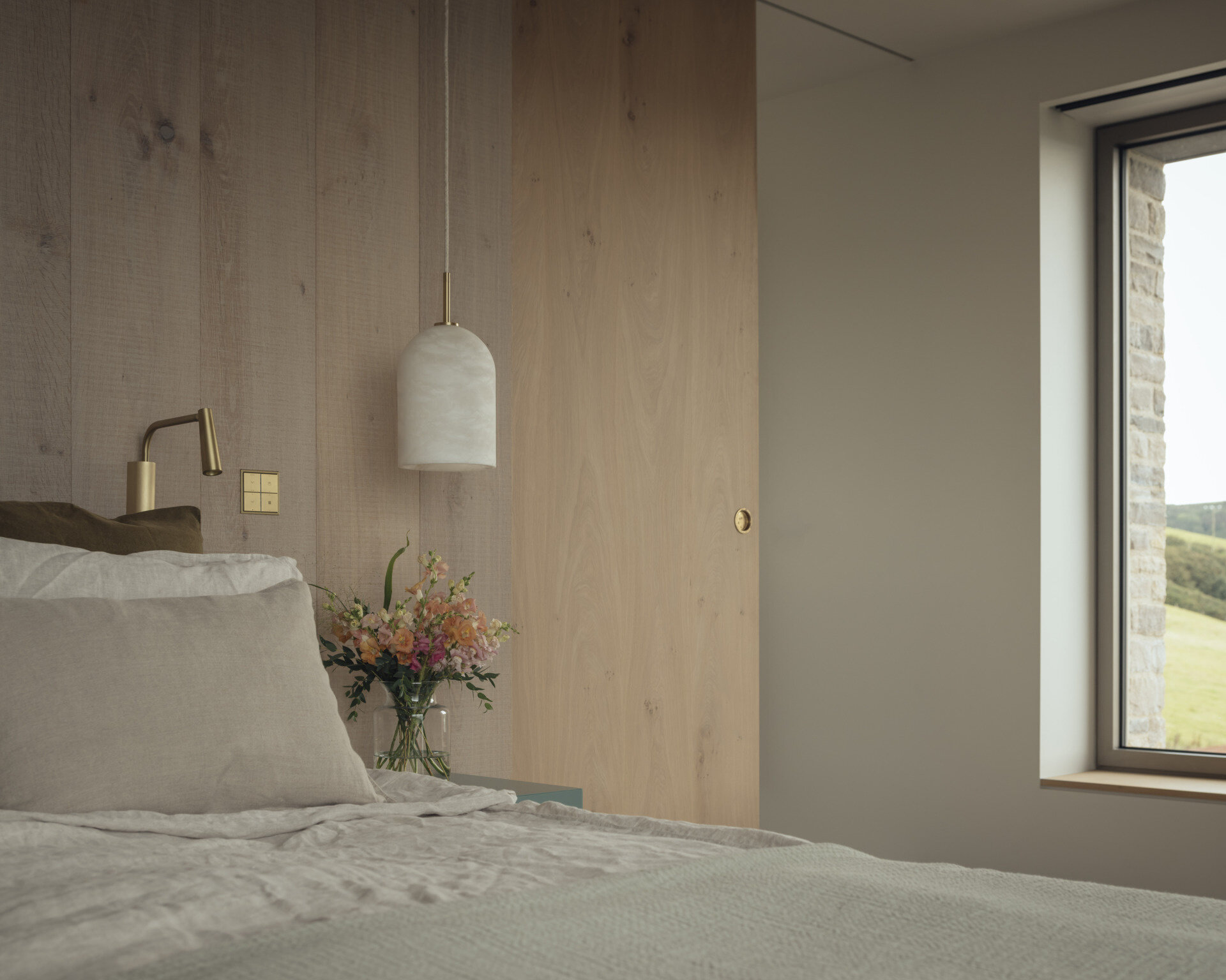 A modern bedroom with a wood accent wall has a sliding door that opens to reveal the ensuite bathroom.