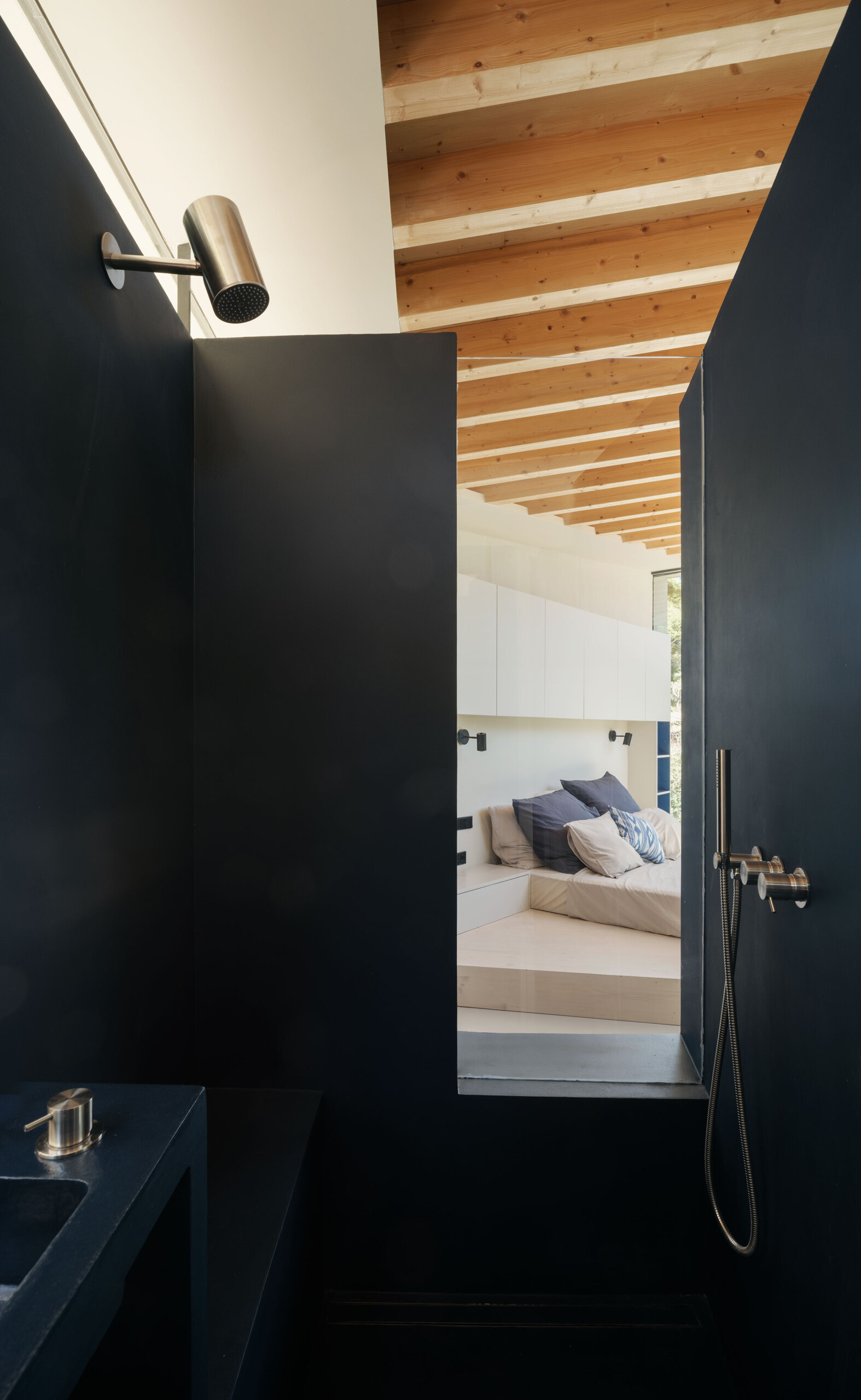 At Can Tudó, the bedrooms flow seamlessly into open bathrooms, with freestanding tubs, sinks, and wardrobes arranged as sculptural dividers. These floating elements define space without enclosing it, allowing every corner to capture uninterrupted views of the bay.