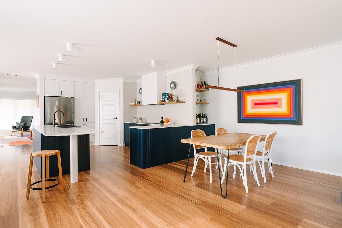 Flowing from the kitchen, the dining area naturally draws family and friends together. Vibrant, colorful commissioned artwork by Mat Vaughan adds energy and personality, making the space feel lively and unique.