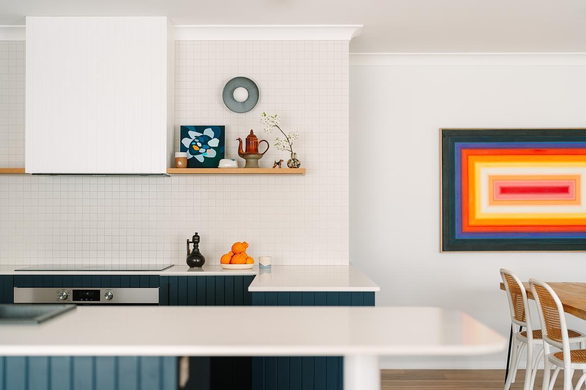 Removing a wall opened this remodeled kitchen to the dining and living areas. Custom royal blue joinery, a central island, and layered lighting created a bold, flexible kitchen hub.