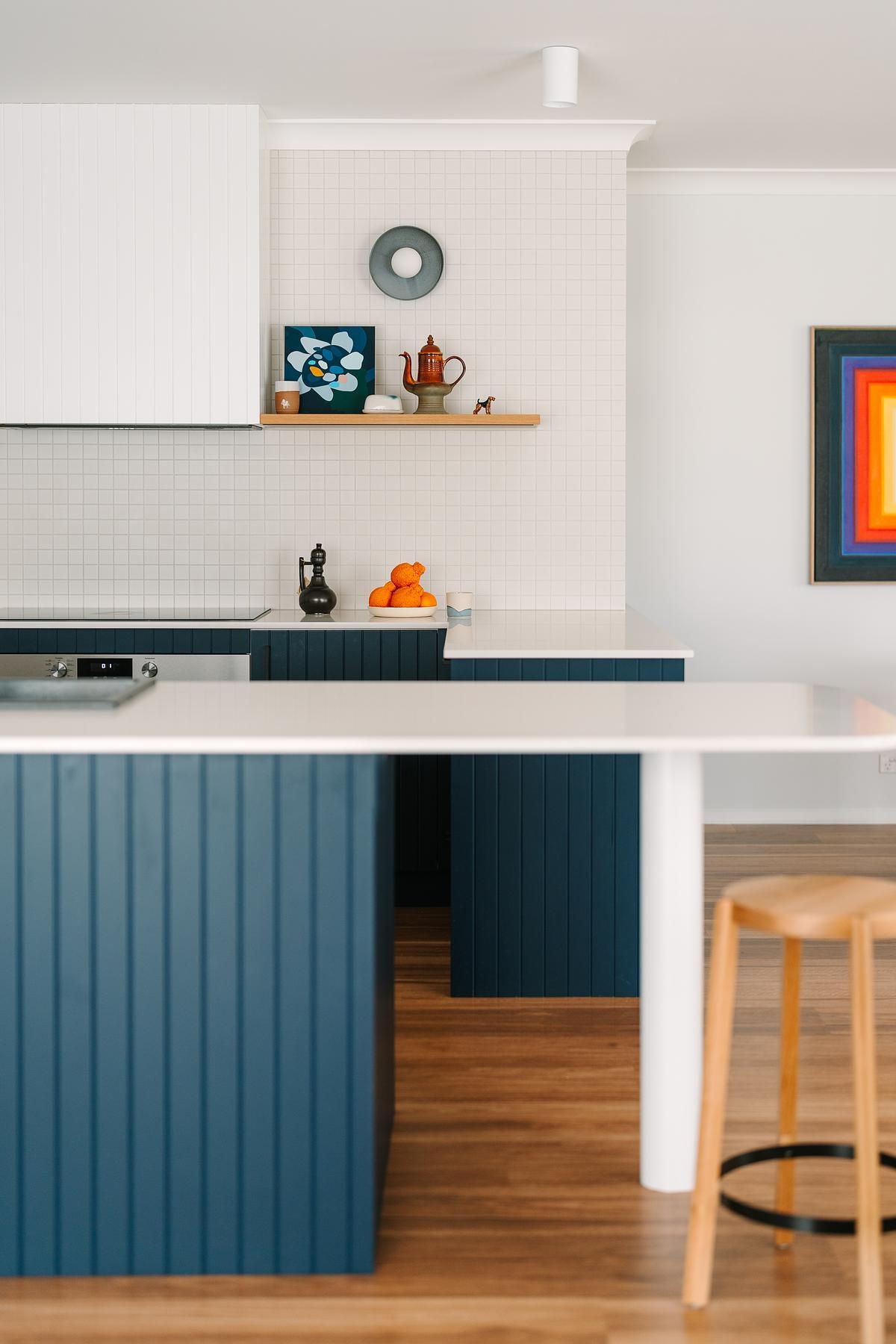 Removing a wall opened this remodeled kitchen to the dining and living areas. Custom royal blue joinery, a central island, and layered lighting created a bold, flexible kitchen hub.