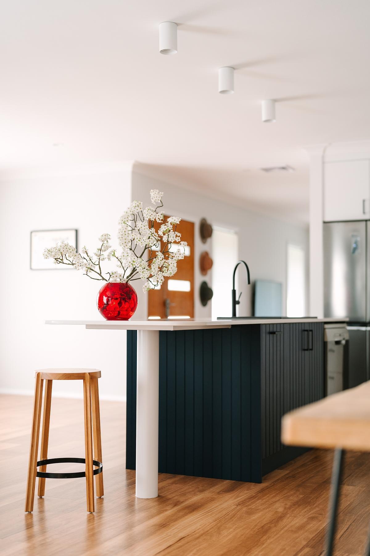 Removing a wall opened this remodeled kitchen to the dining and living areas. Custom royal blue joinery, a central island, and layered lighting created a bold, flexible kitchen hub.