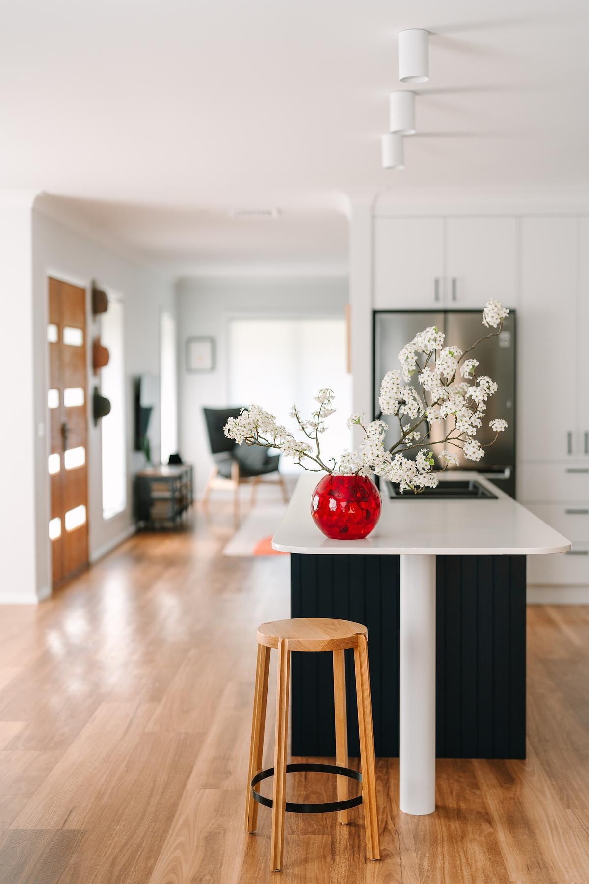 Removing a wall opened this remodeled kitchen to the dining and living areas. Custom royal blue joinery, a central island, and layered lighting created a bold, flexible kitchen hub.