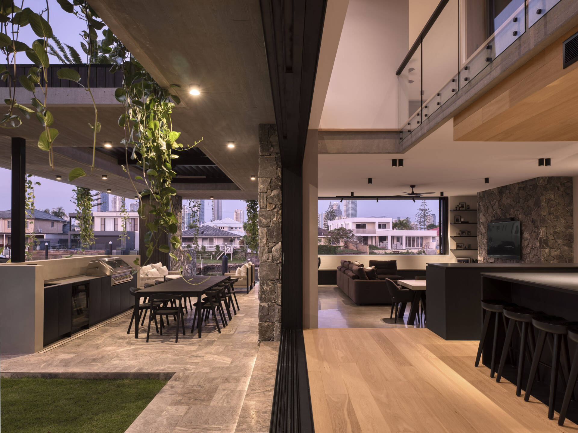 Shaded outdoor zones extend the living spaces. Here, subtropical overhangs and battened screens protect against sun and rain while maintaining openness. An outdoor kitchen and living room encourages casual gatherings and celebrates indoor-outdoor living, a hallmark of the home’s climate-sensitive design.