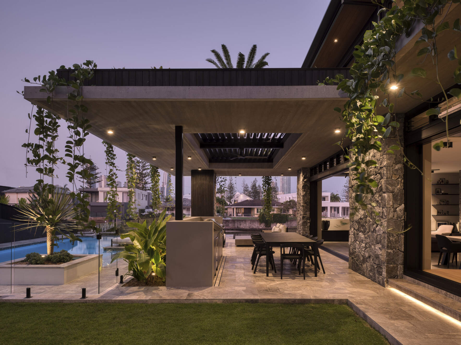Shaded outdoor zones extend the living spaces. Here, subtropical overhangs and battened screens protect against sun and rain while maintaining openness. An outdoor kitchen and living room encourages casual gatherings and celebrates indoor-outdoor living, a hallmark of the home’s climate-sensitive design.