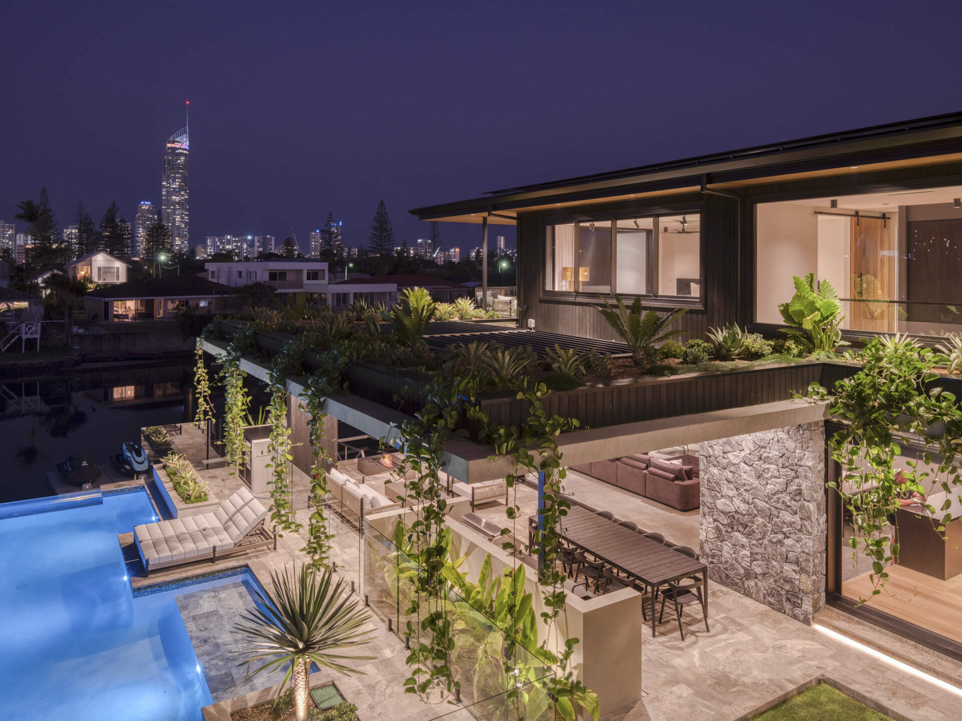 Shaded outdoor zones extend the living spaces. Here, subtropical overhangs and battened screens protect against sun and rain while maintaining openness. An outdoor kitchen and living room encourages casual gatherings and celebrates indoor-outdoor living, a hallmark of the home’s climate-sensitive design.