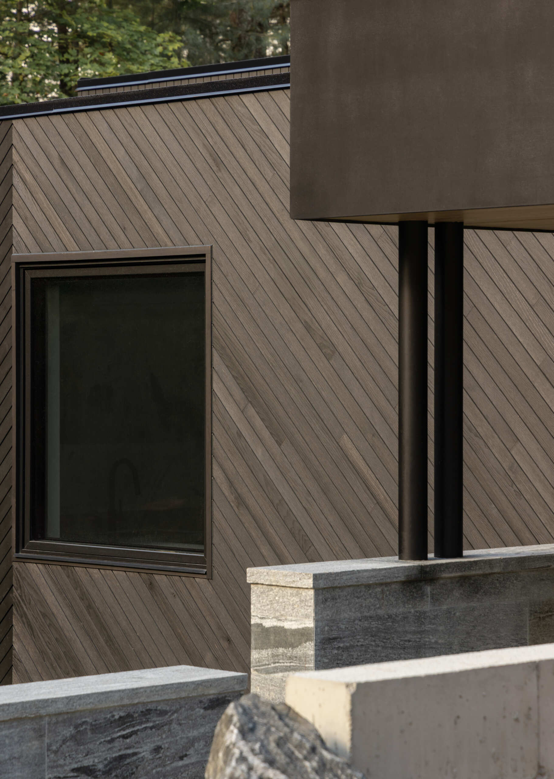 Black timber cladding and glass define the exterior of this modern lake cottage, striking yet rooted in the forest.