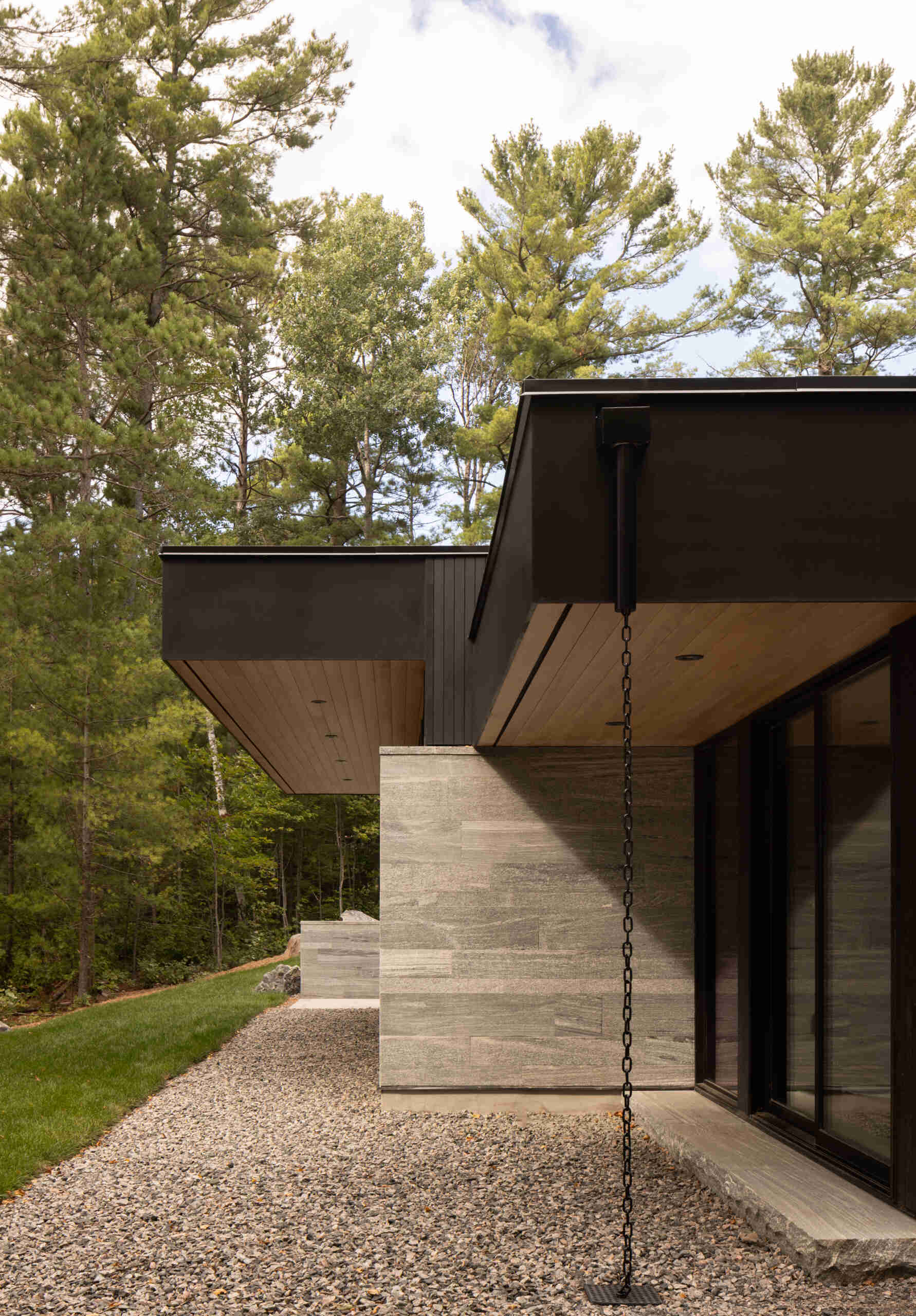 Black timber cladding and glass define the exterior of this modern lake cottage, striking yet rooted in the forest.