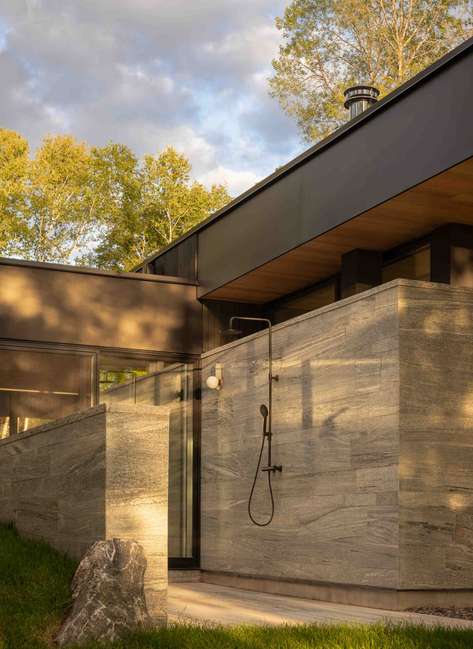 Black timber cladding and glass define the exterior of this modern lake cottage, striking yet rooted in the forest.